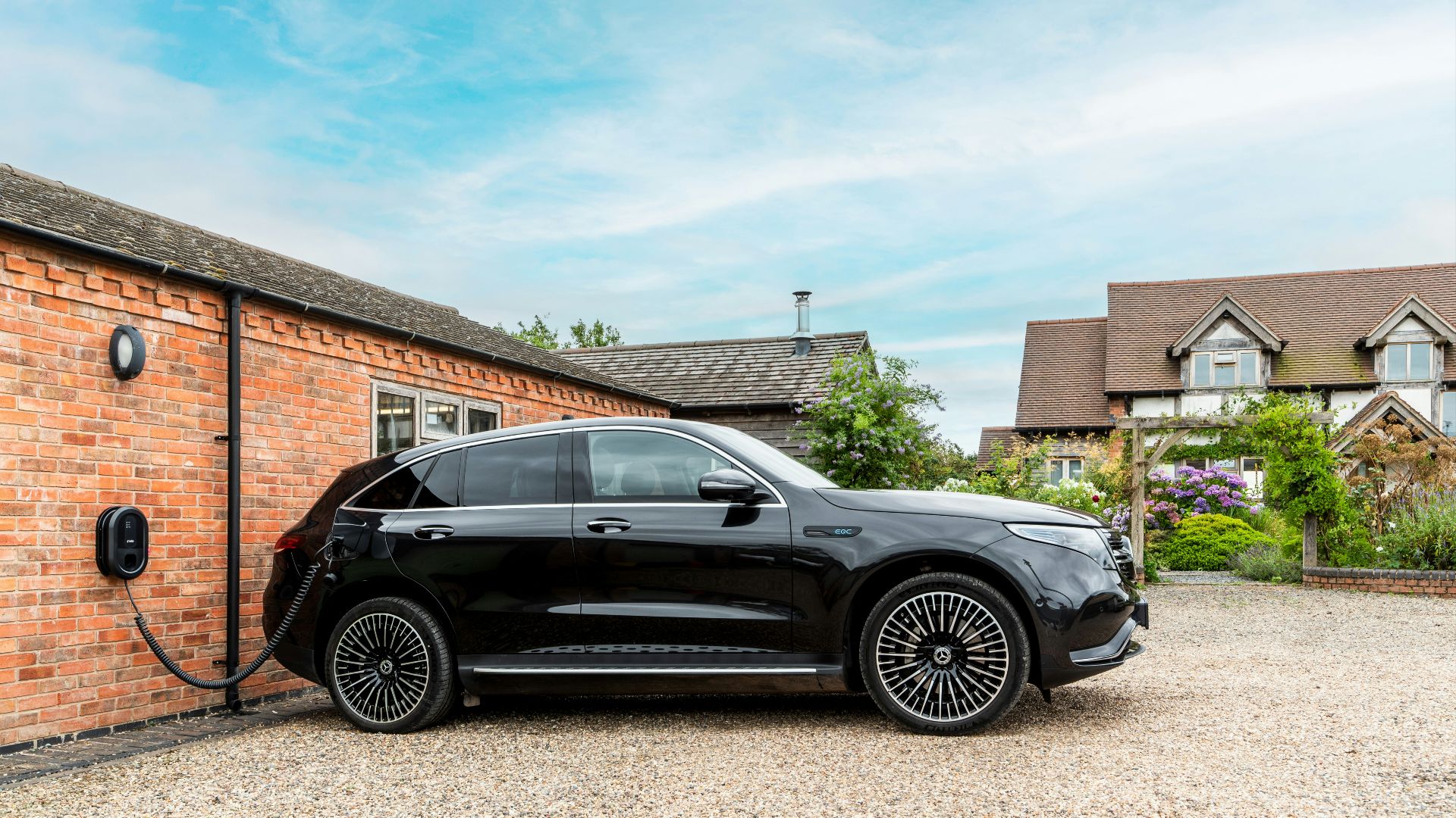 Black electric car charging next to brick building