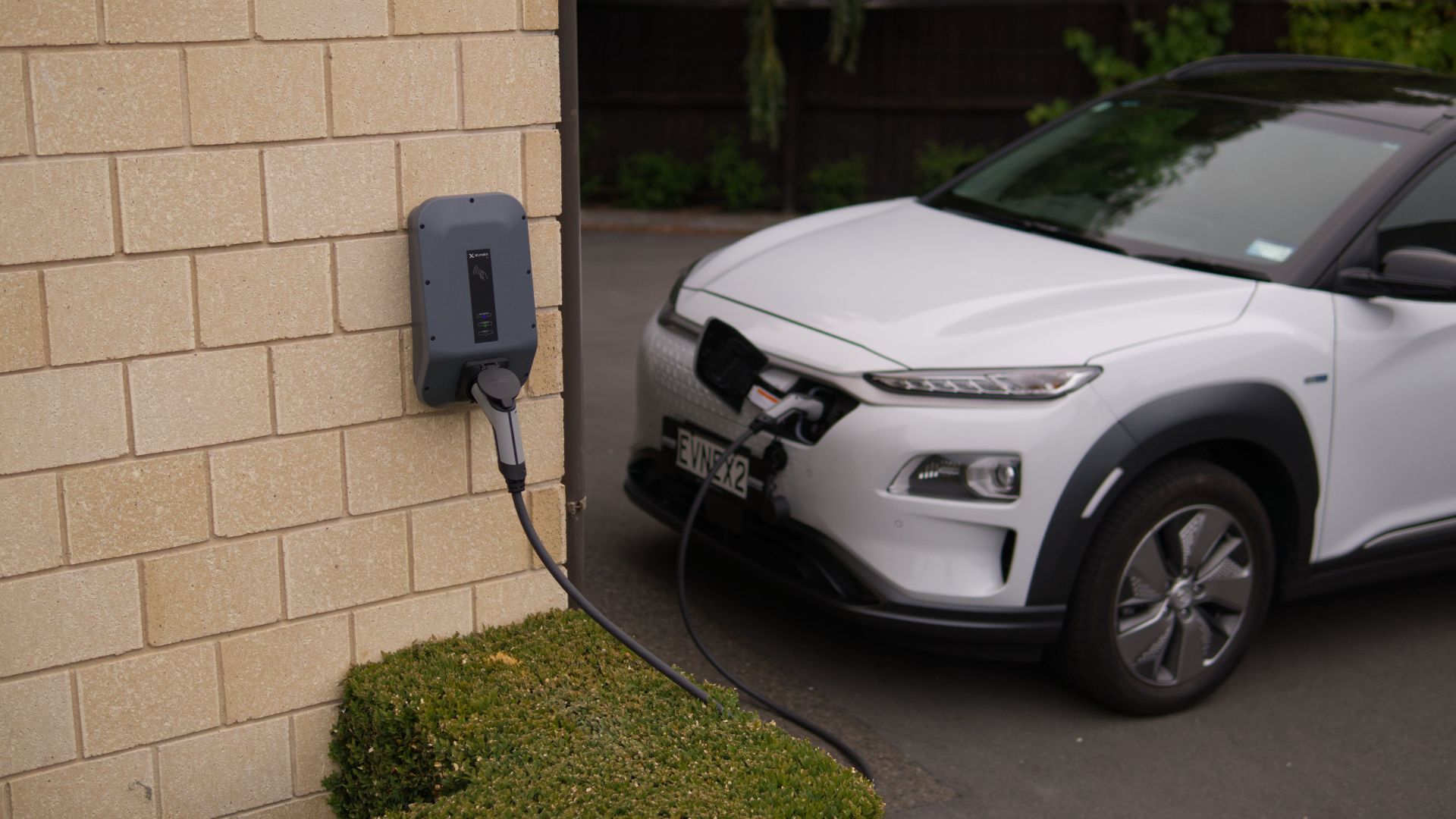 A white electric car charging at a station in Christchurch, New Zealand, showcasing modern eco-friendly transportation.