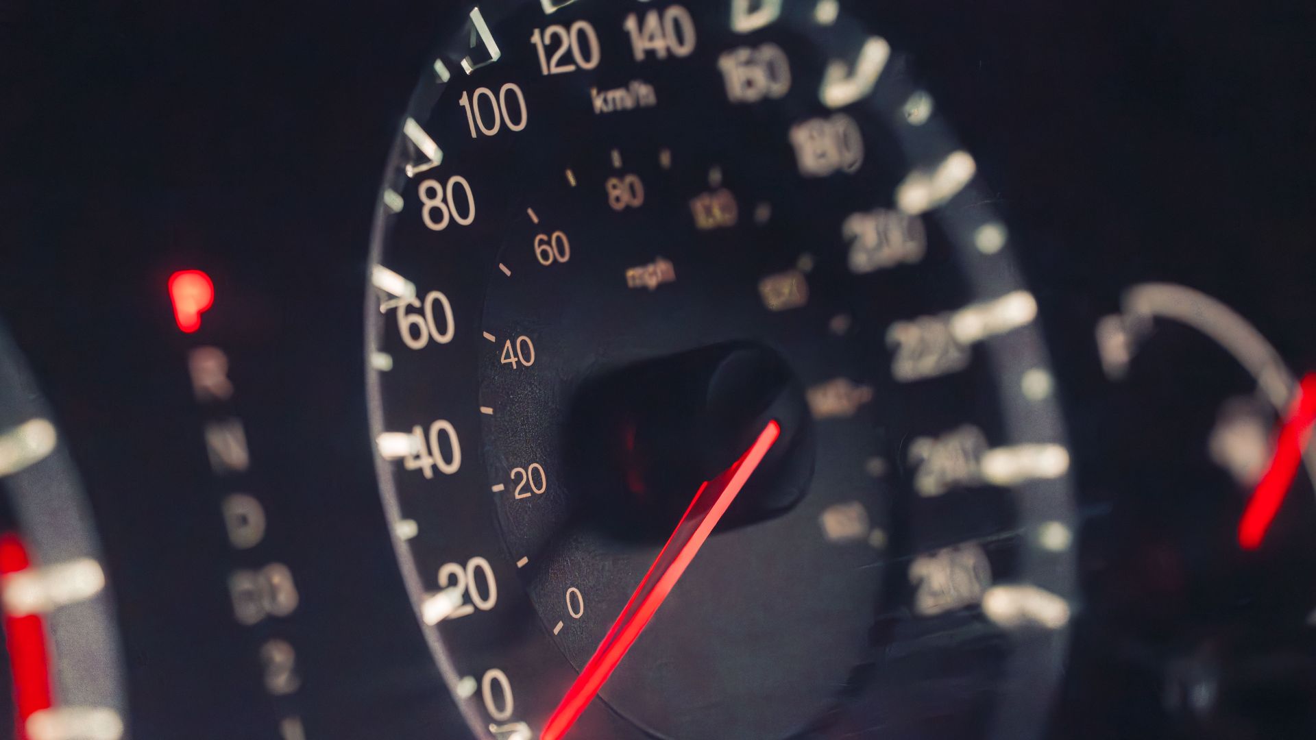 Detailed view of a car speedometer showing km/h and mph in low light settings.