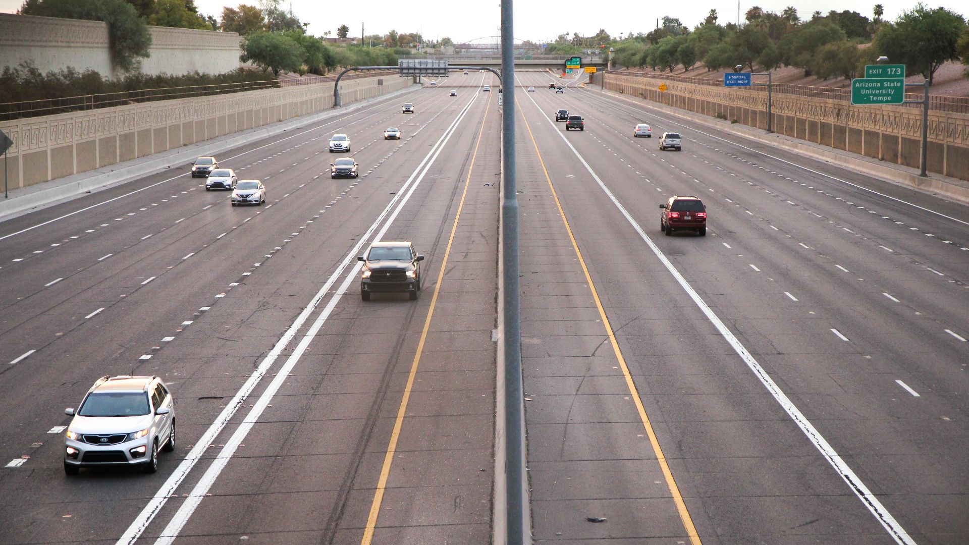Aerial view of a deserted highway with few cars during dusk, depicting calm traffic conditions.