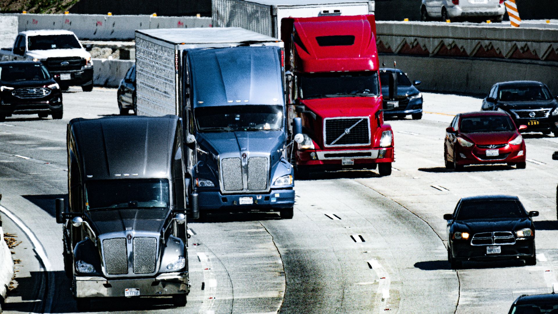 Trucks and cars traveling on a congested city highway during the day.
