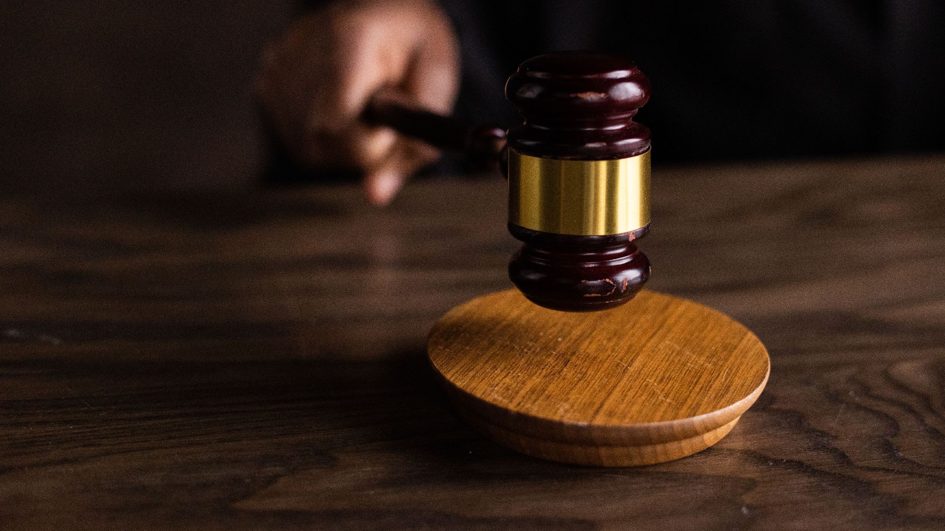 A gavel striking a sound block, symbolizing justice and legal authority in a courtroom setting.