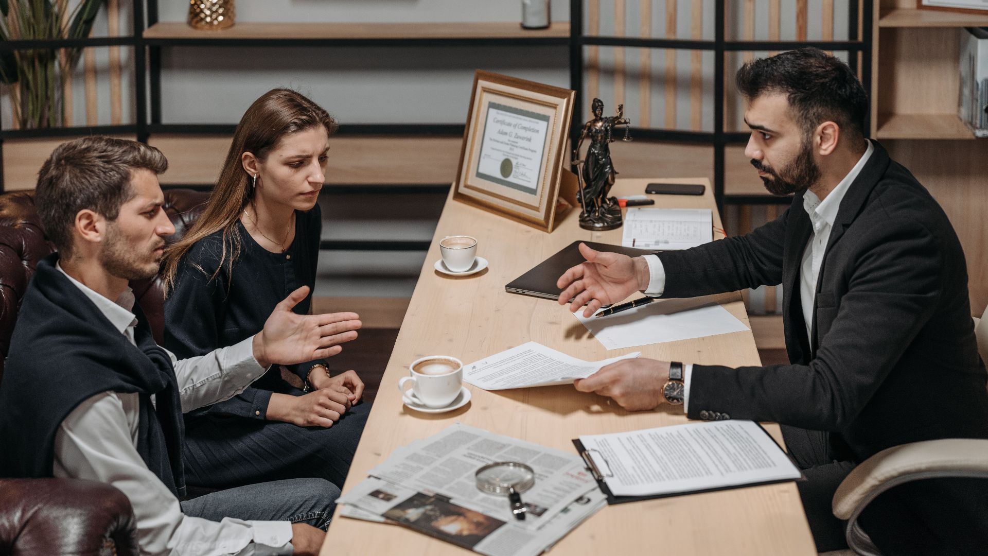Lawyer consulting clients in an office. Documents and coffee on the table.