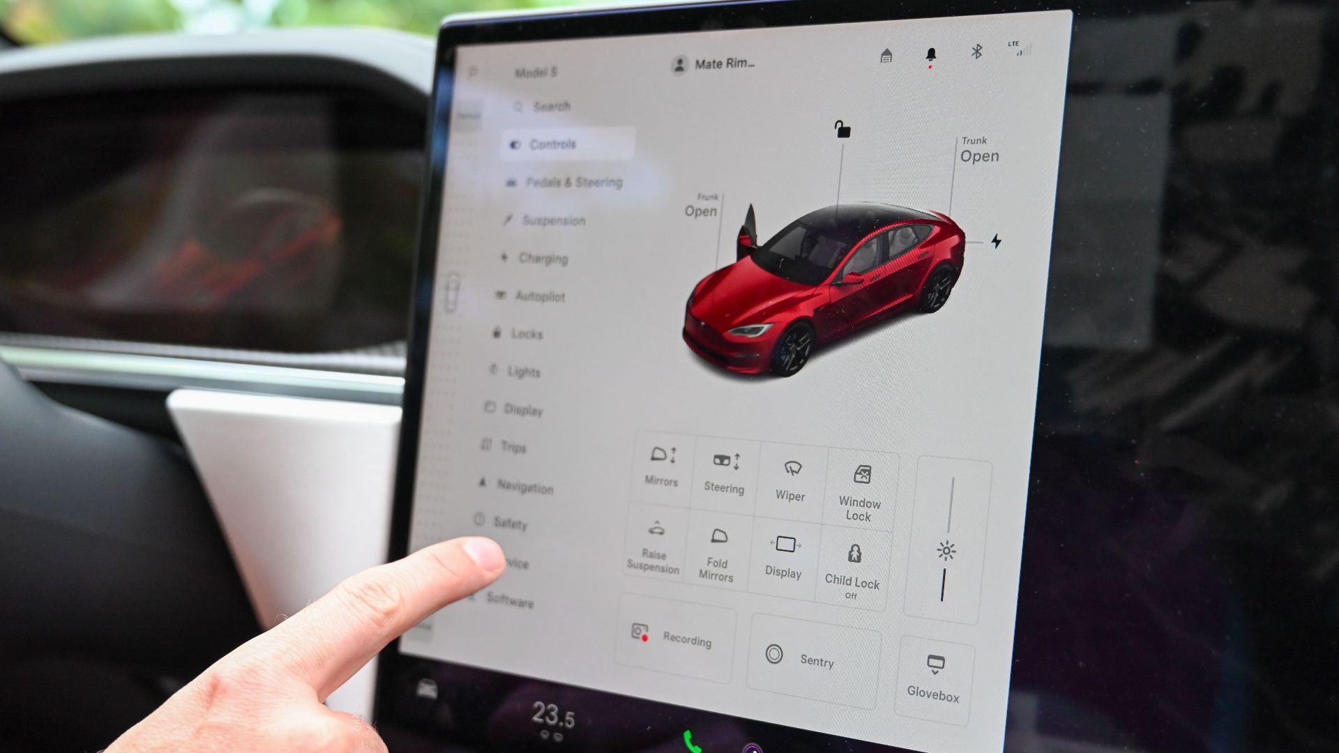 Close-up of a hand interacting with a modern car's touchscreen interface for various controls.