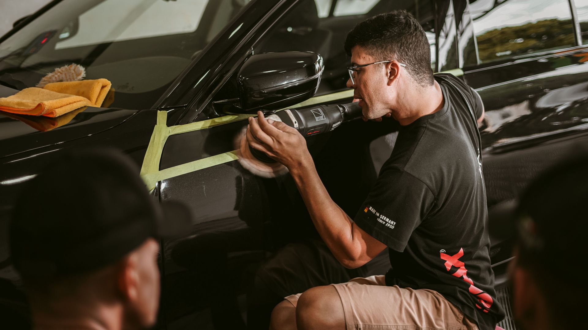 A man meticulously polishes a car, showcasing precision in an automotive workshop.