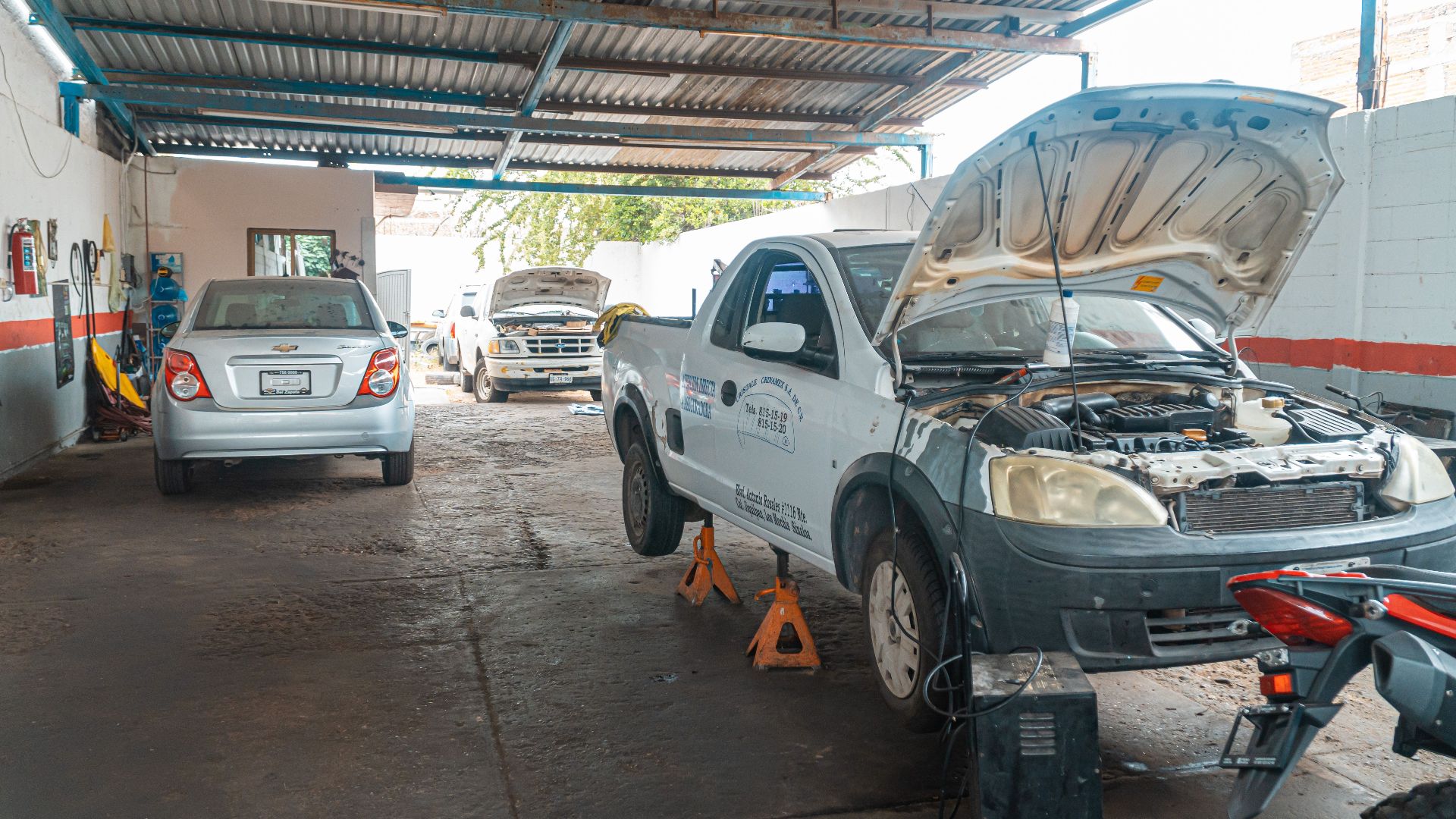 Indoor car repair garage with multiple vehicles under maintenance, showcasing a bustling automotive environment.
