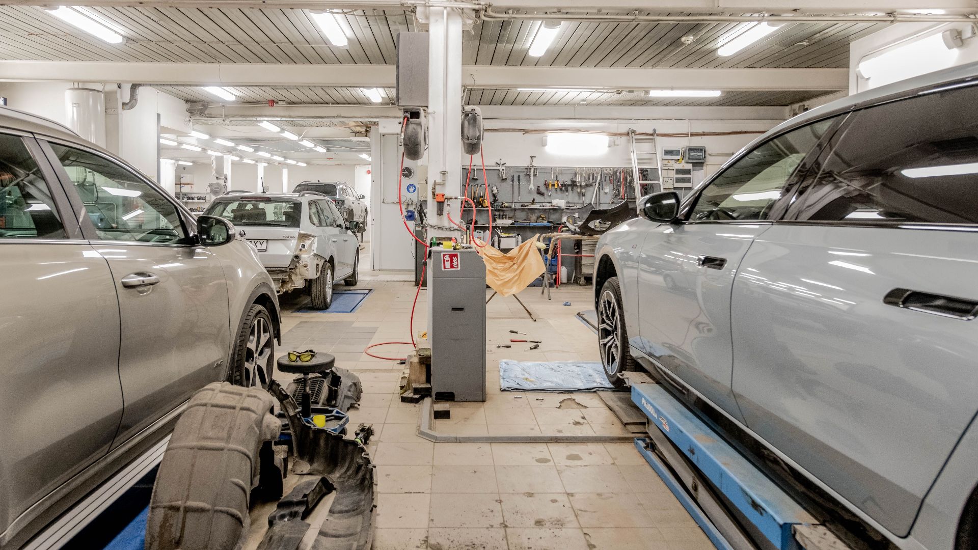 Interior of an automotive repair shop with cars undergoing maintenance and servicing.