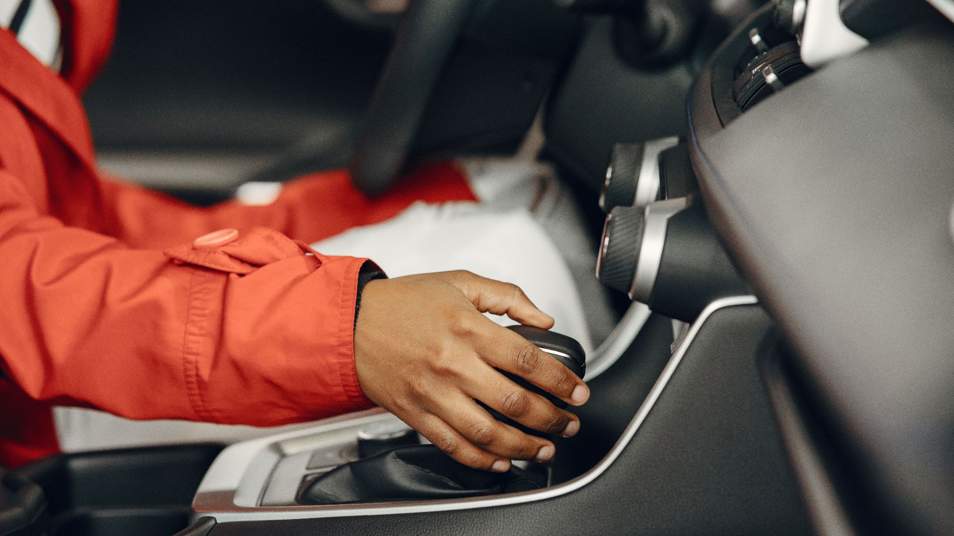 Close-up view of a person shifting gears in a car interior, illustrating driving expertise.