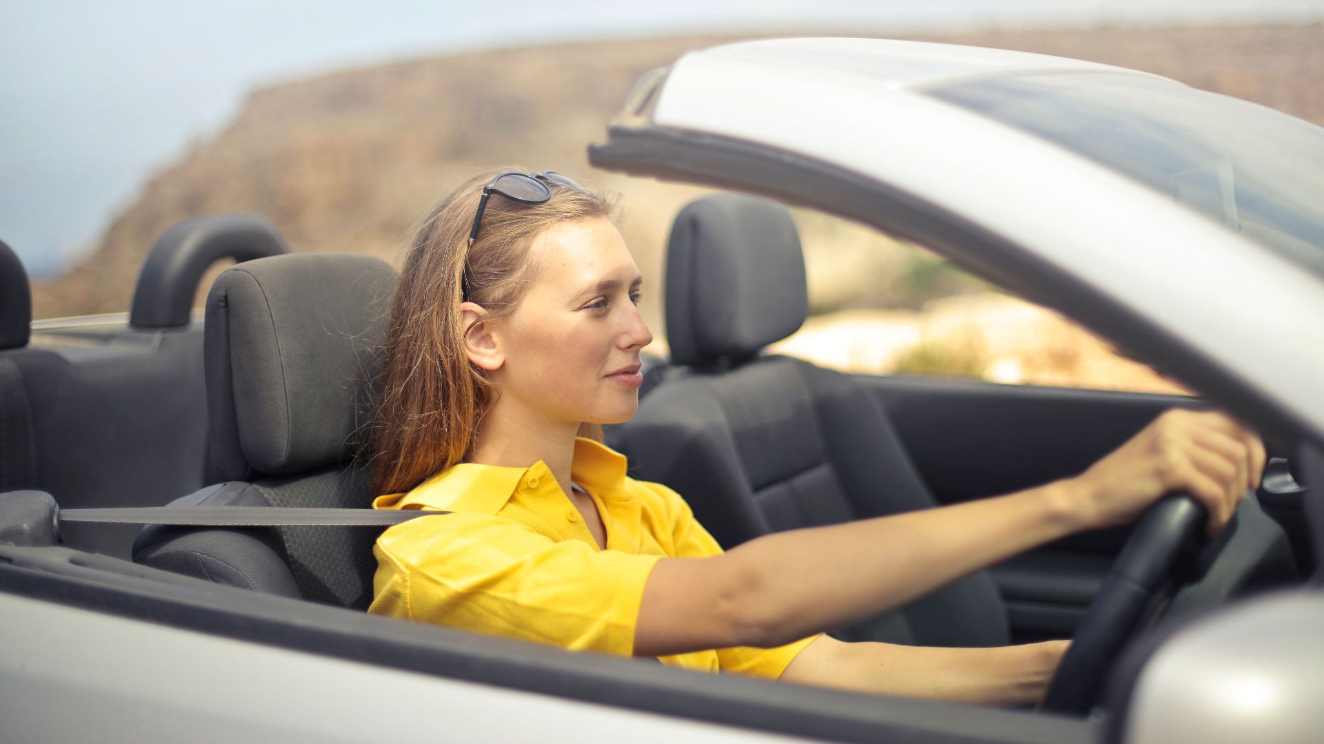 A young woman enjoys driving a convertible on a sunny day in Malta.