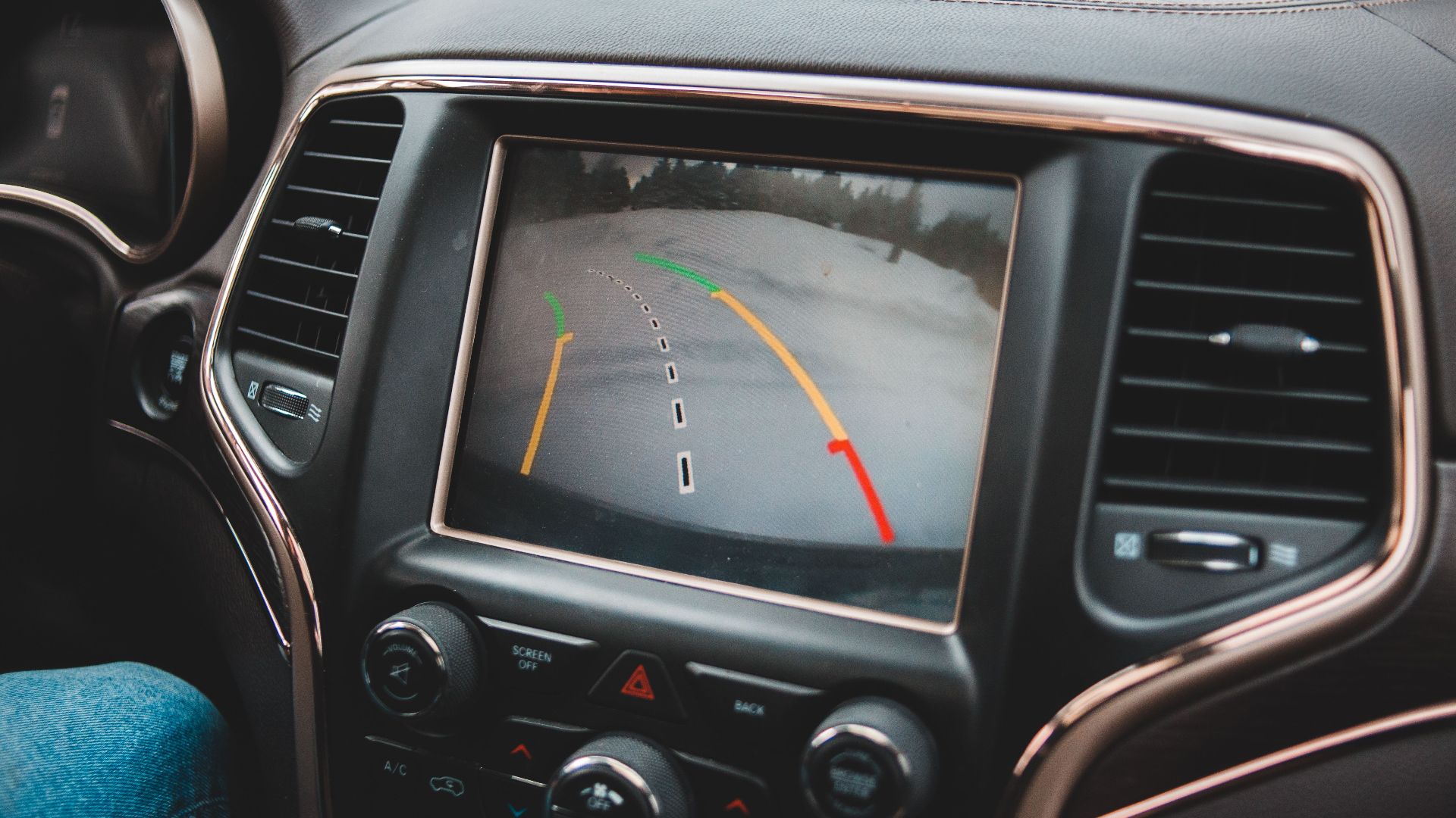 Close-up of a car's dashboard showing a rearview camera display for parking assistance.