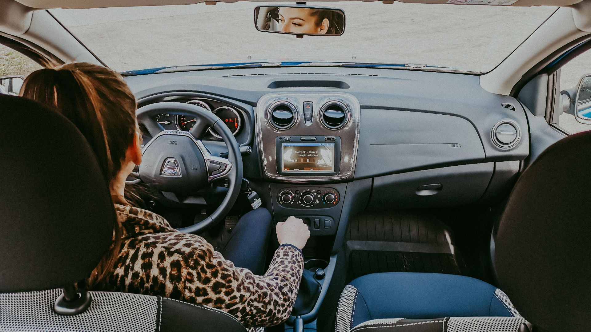 Back view of modern woman in stylish fur coat driving car confidently looking away