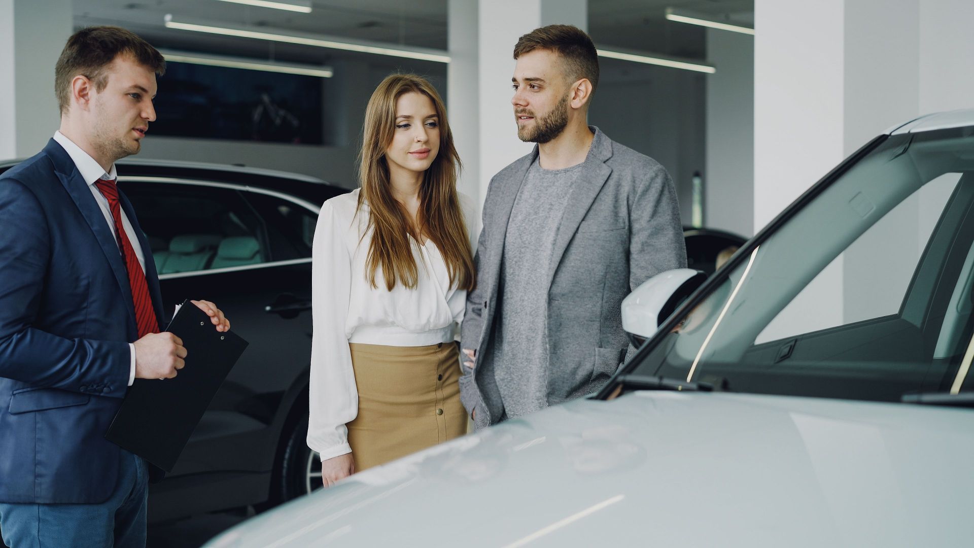 Couple discussing options with a car salesman inside a dealership.