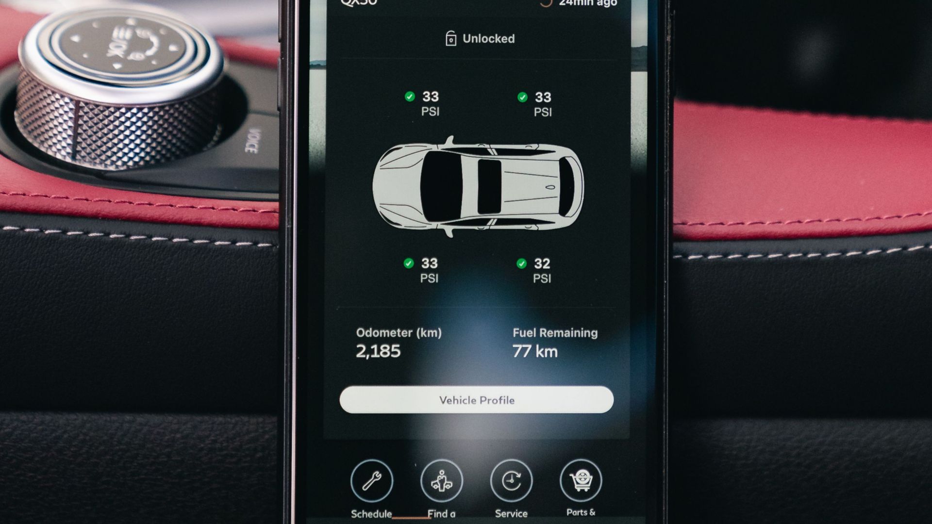 A smartphone showing a car dashboard app interface, placed inside a vehicle.