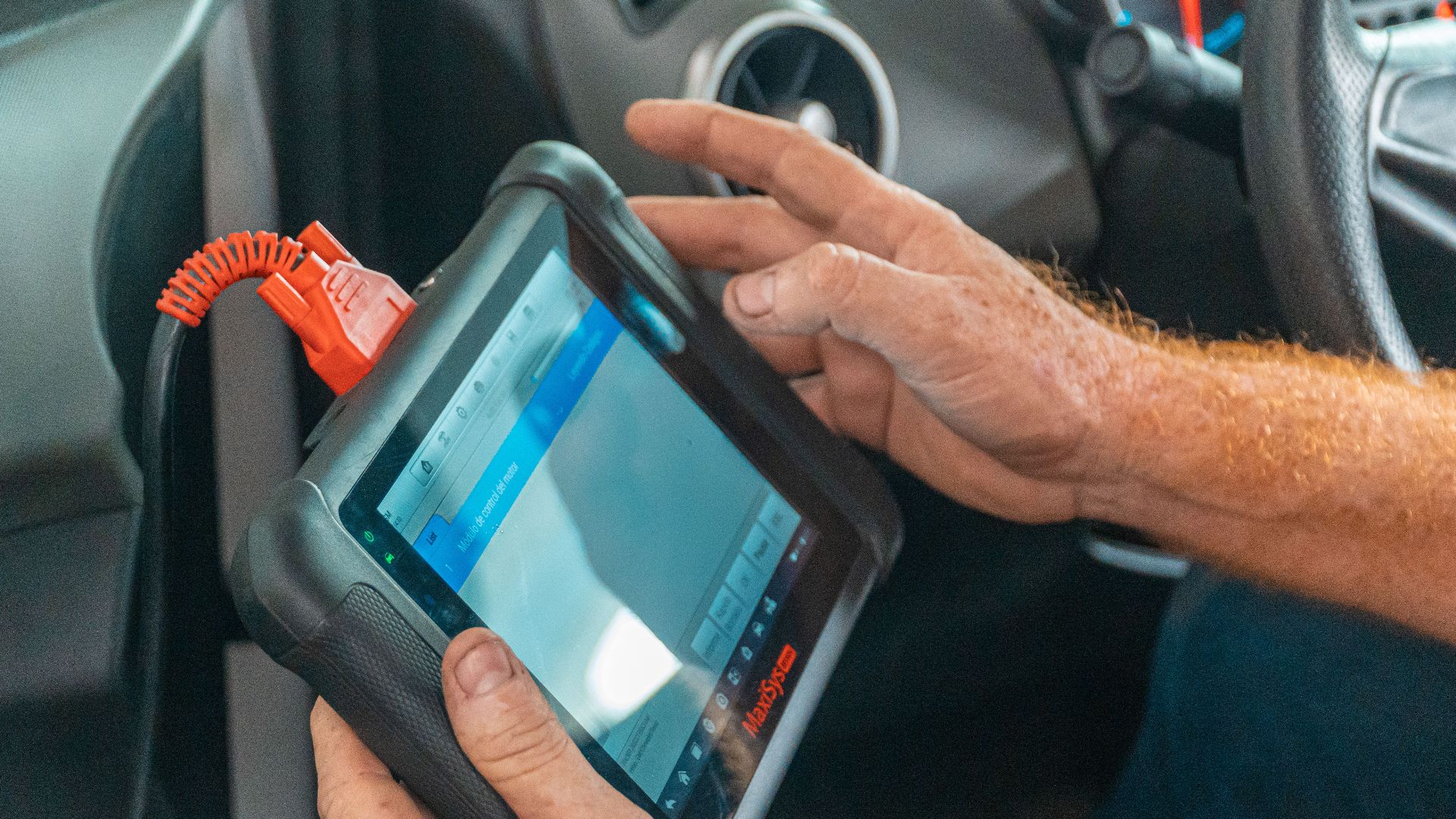 A mechanic uses a diagnostic tablet inside a car for vehicle analysis.