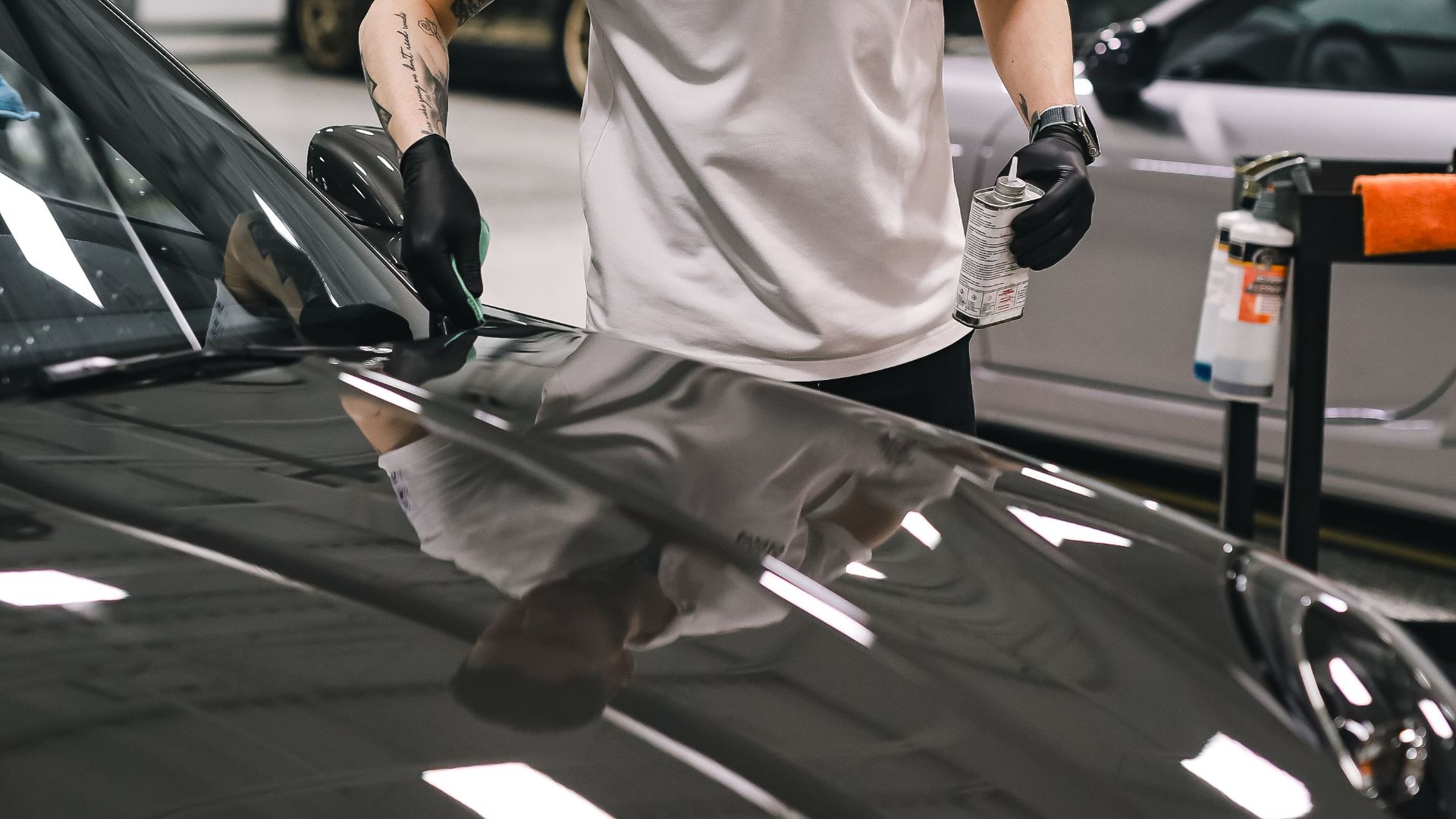 A dedicated employee expertly detailing a car hood in a clean, modern garage setting.