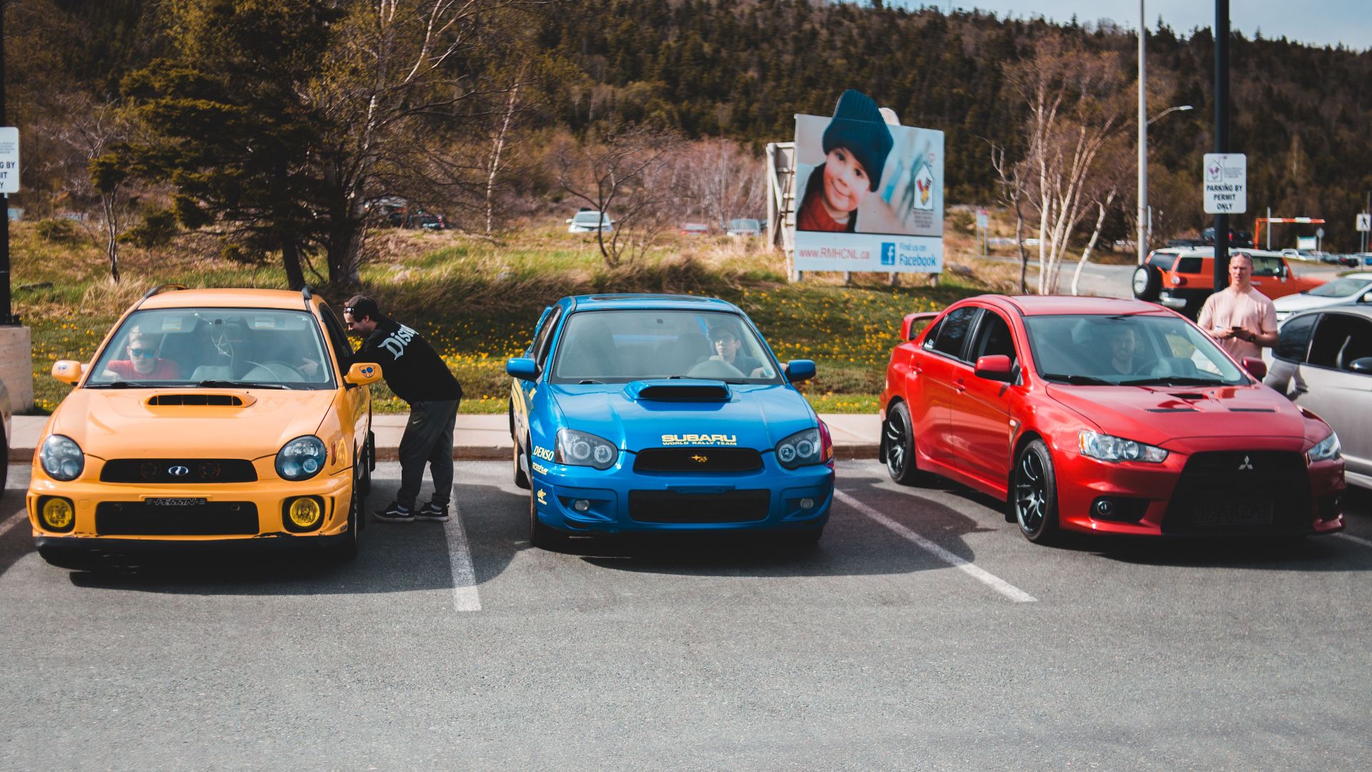 Colorful cars showcased outdoors in an urban parking lot on a sunny day.