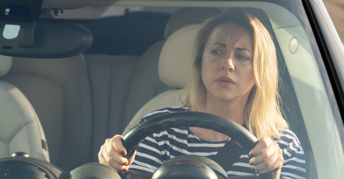 Scared woman driver worried looking at car accident on road through windshield.