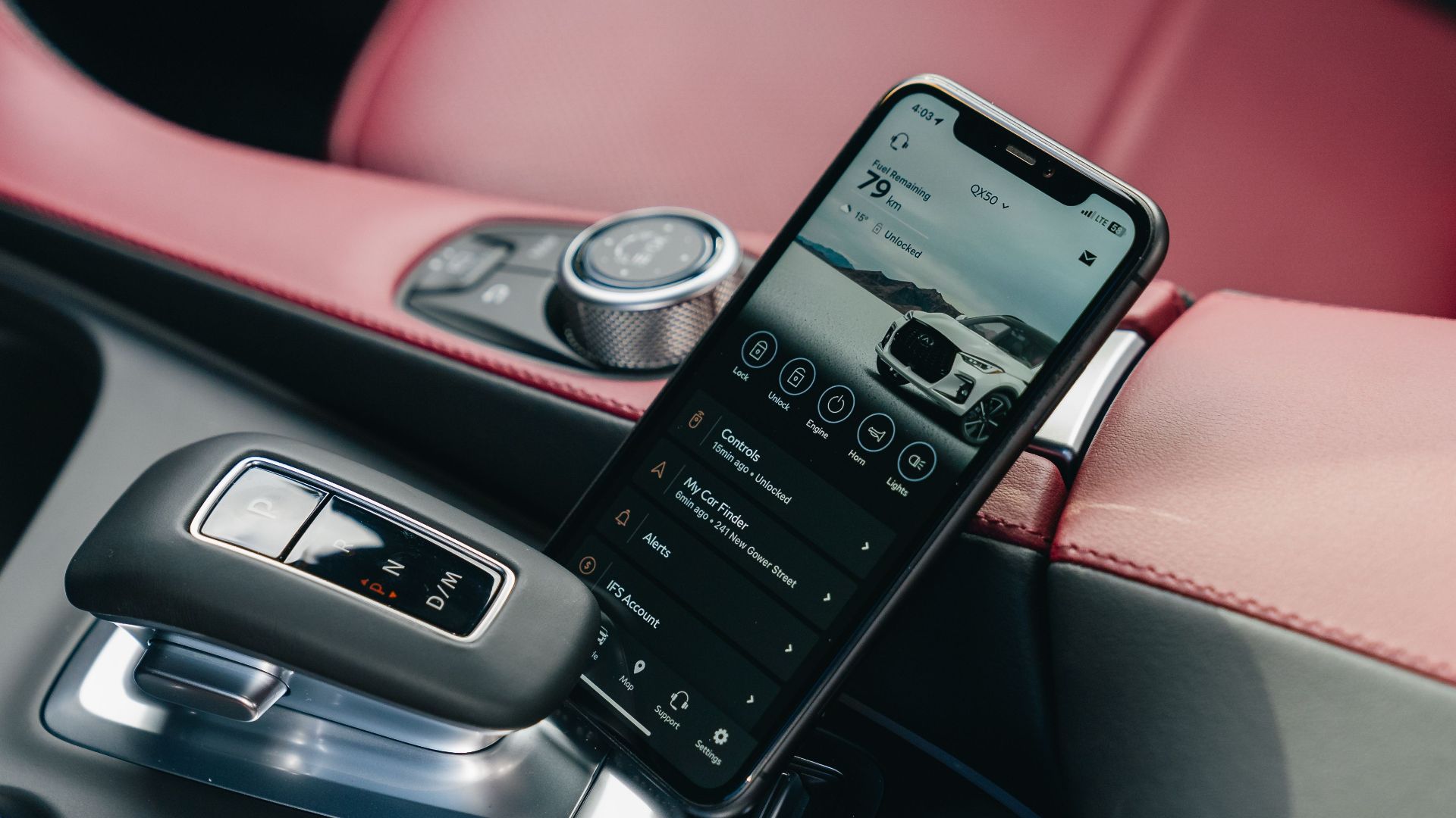 Close-up of smartphone with car control app in a luxury car's interior, showcasing modern technology.