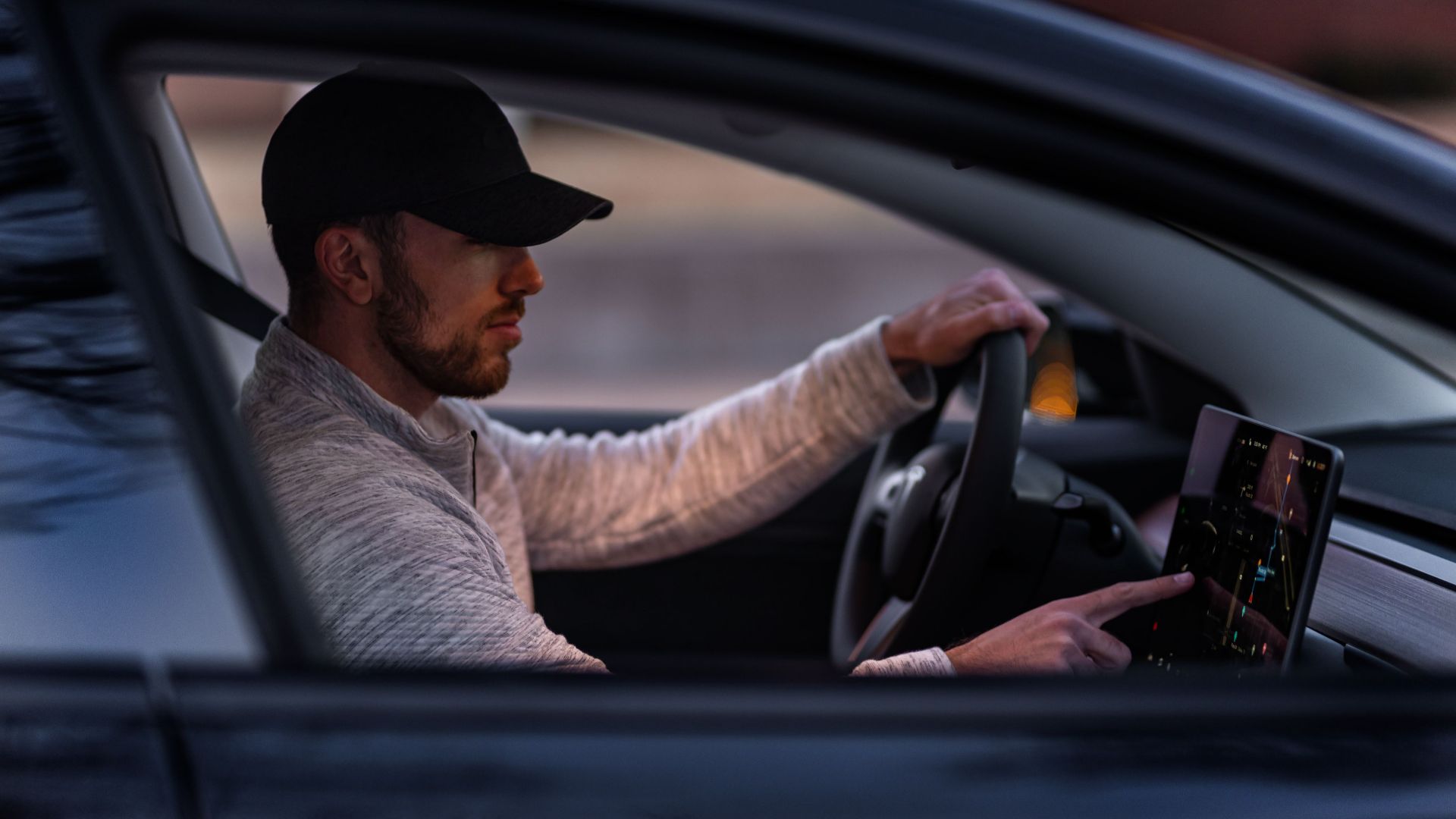 A man interacts with a touchscreen inside an electric car, driving through Dallas, TX.
