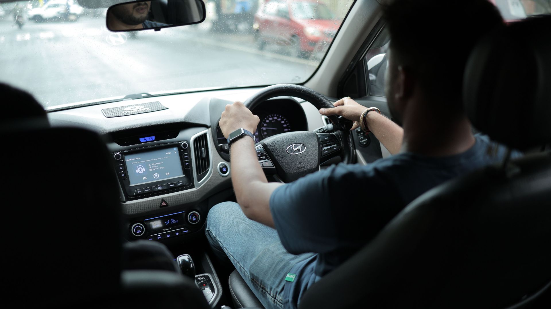 A person drives a Hyundai car while listening to music inside a modern vehicle.