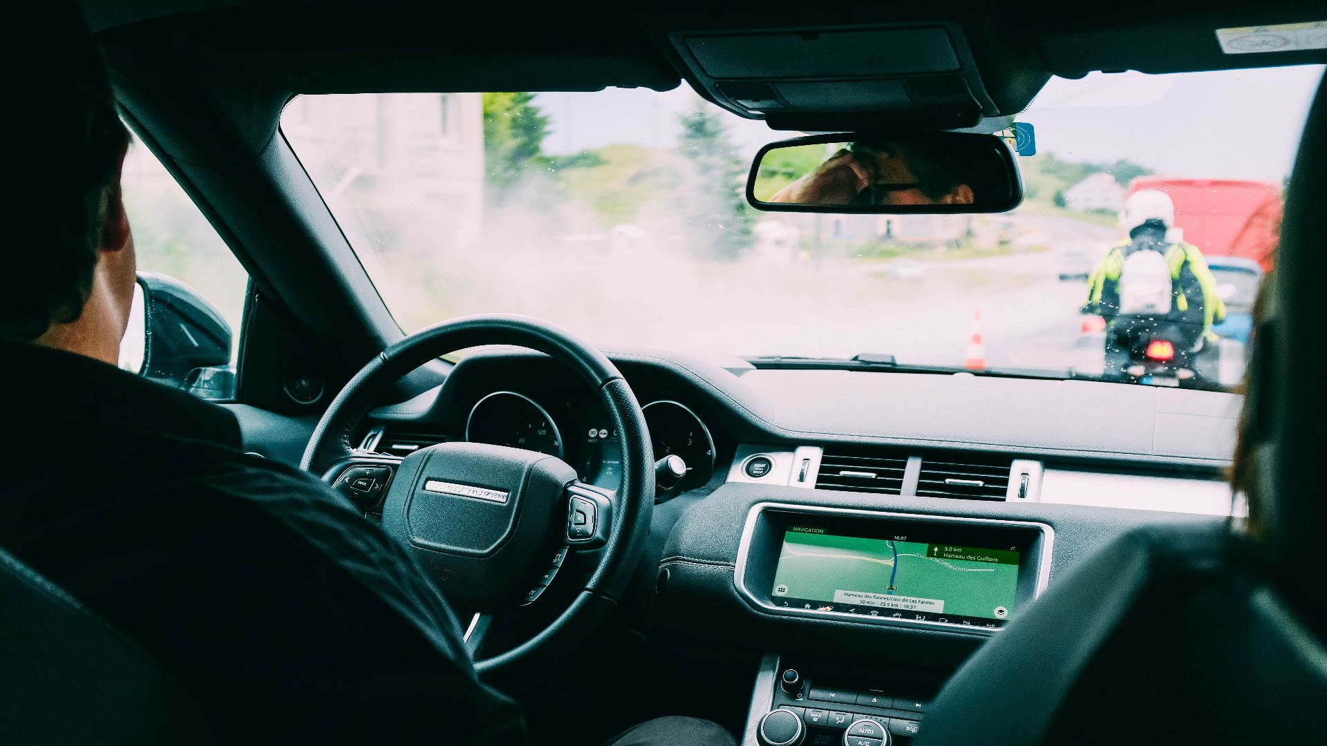 Interior view of a car with GPS navigation and traffic ahead, showcasing urban transportation.