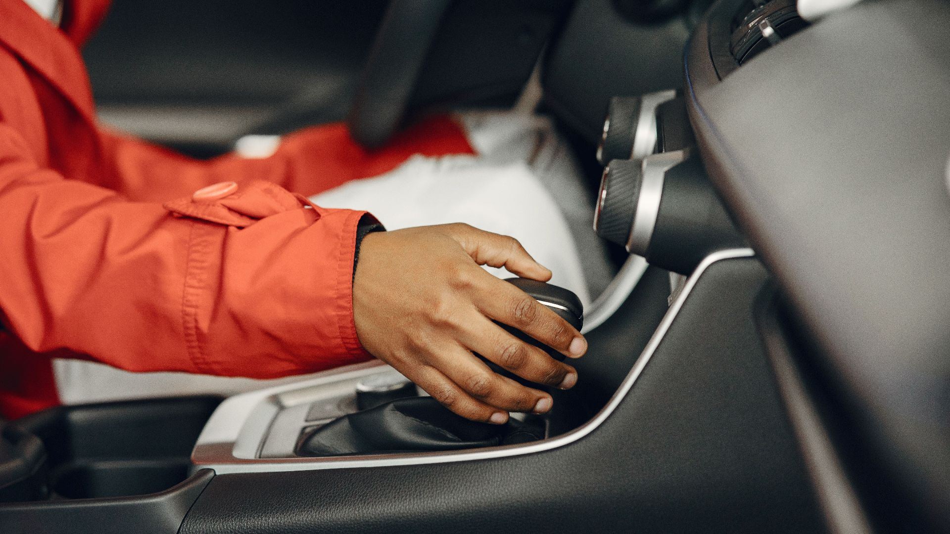 Close-up view of a person shifting gears in a car interior, illustrating driving expertise.
