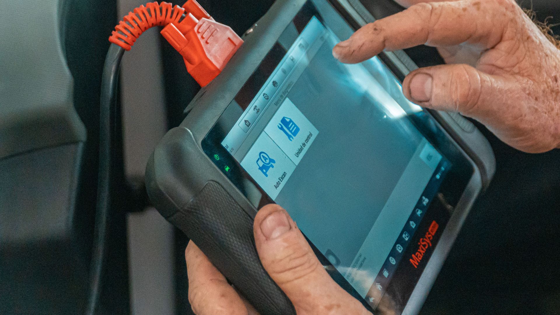 Mechanic using a diagnostic tool inside a car to check for engine issues and ensure proper maintenance.