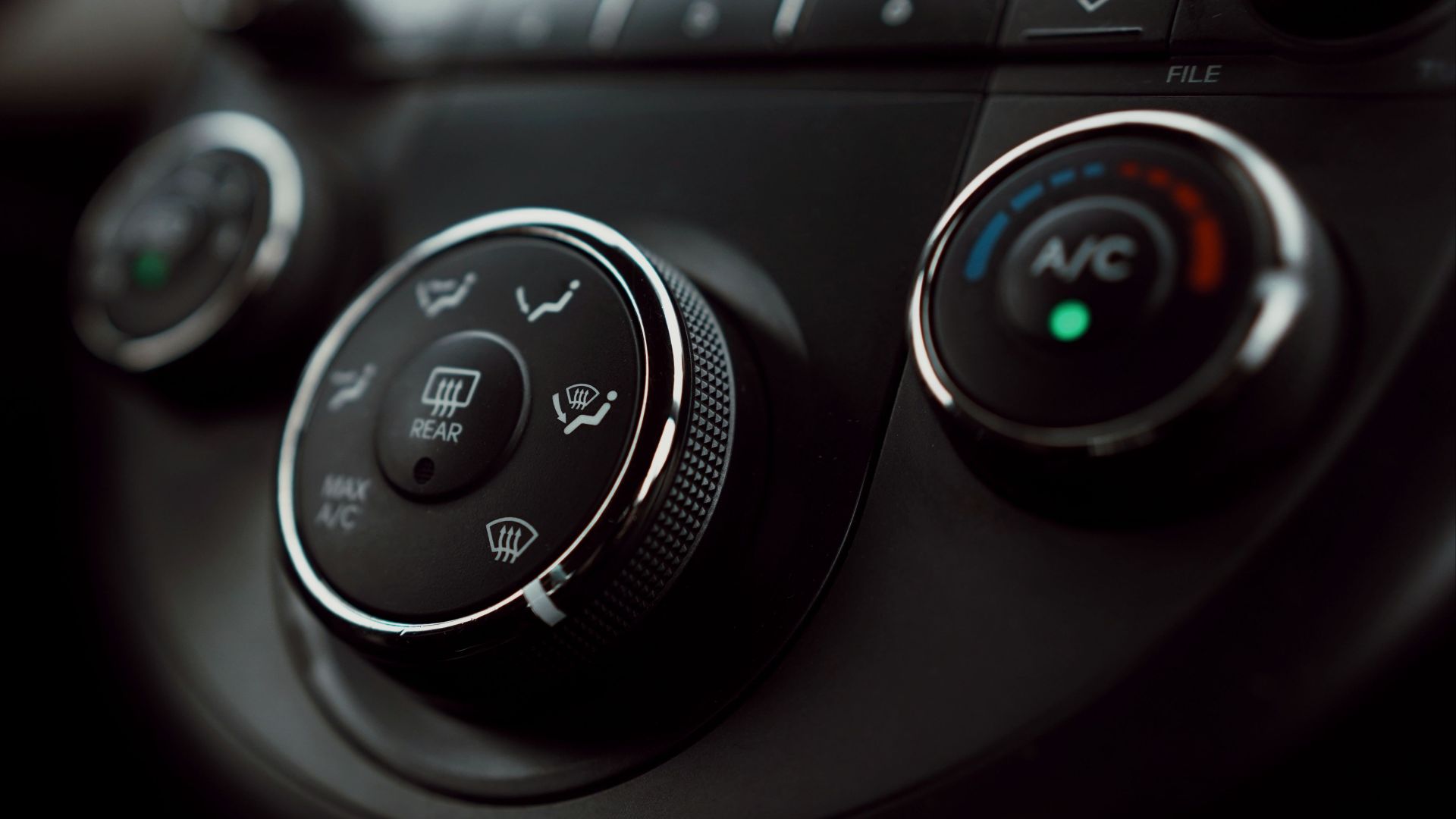 Detailed close-up of car dashboard air conditioning controls with focus on buttons and dials.