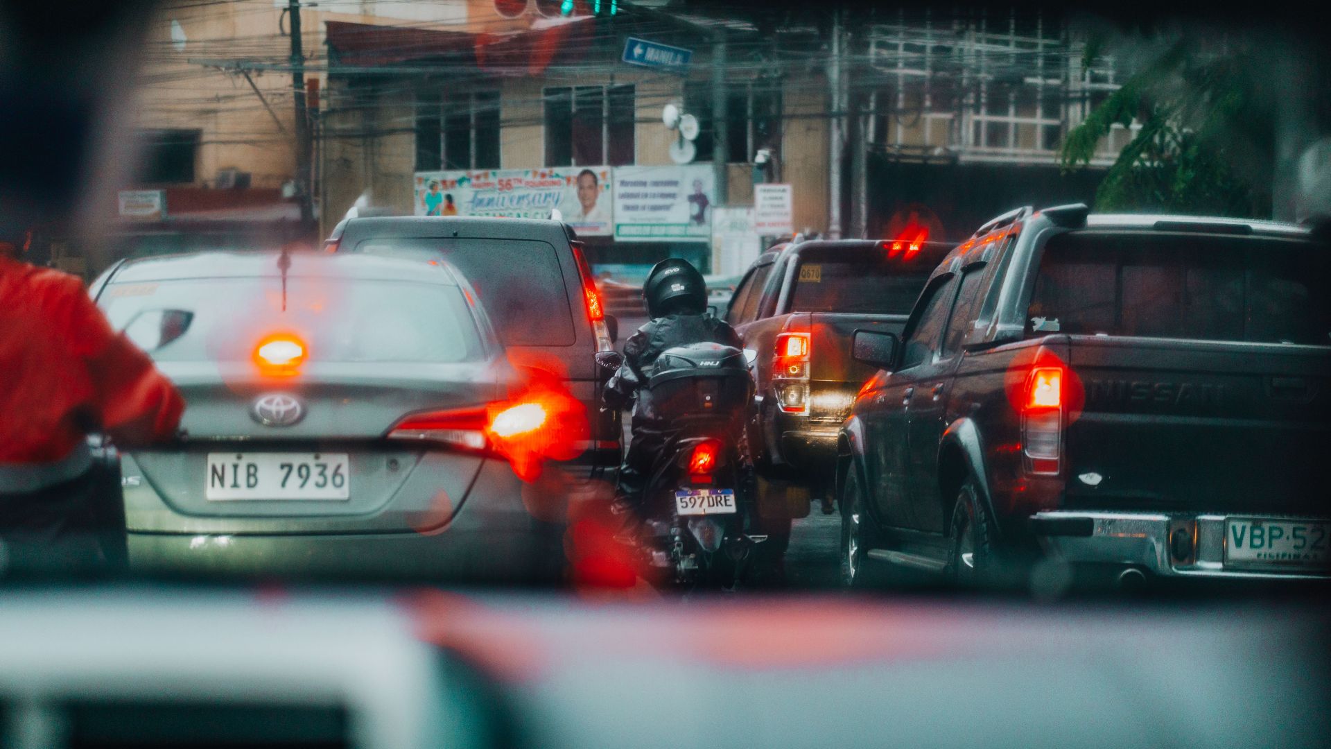 View of a busy urban traffic jam through a car windshield on a rainy day.