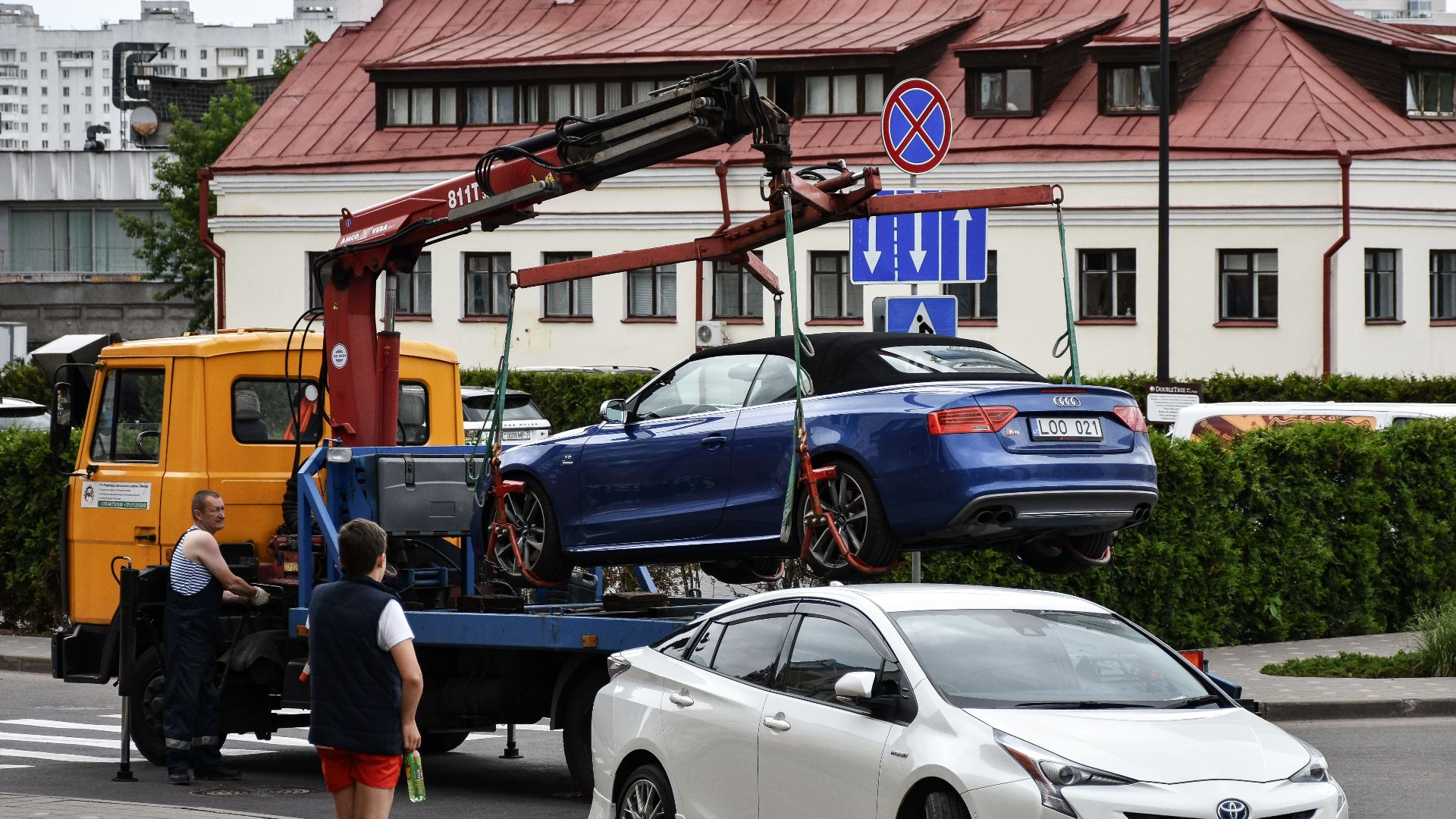 Towing a blue Audi convertible in a bustling city street.
