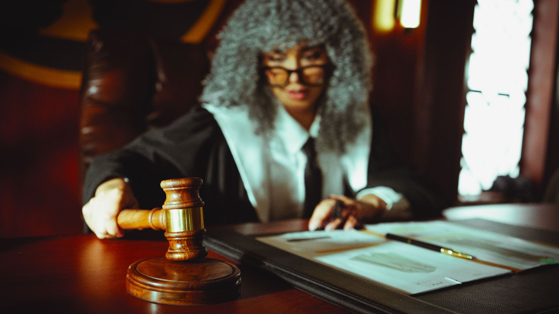 Female judge in a courtroom setting, focusing on legal documents with a gavel.