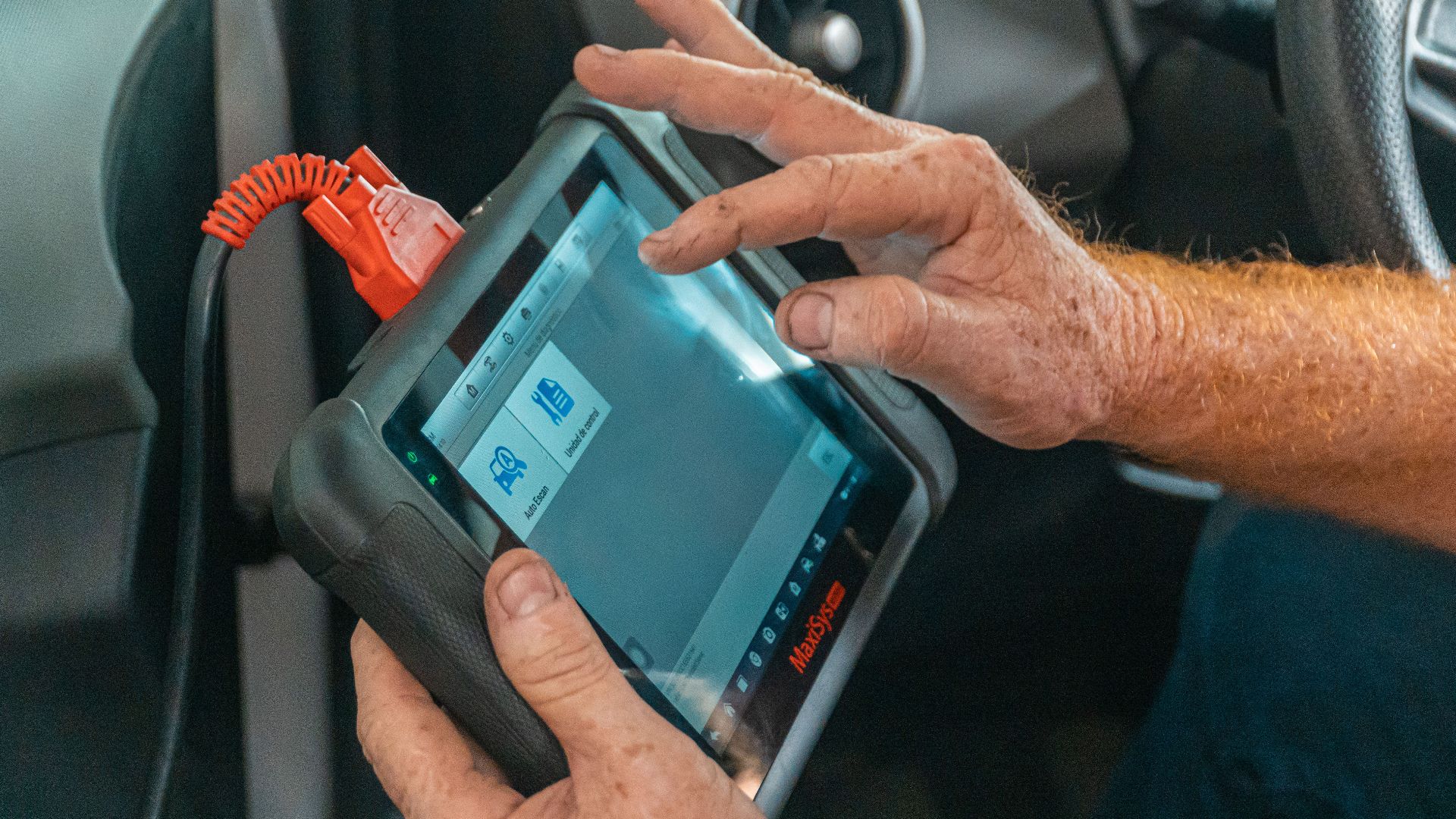 Mechanic using a diagnostic tool inside a car to check for engine issues and ensure proper maintenance.