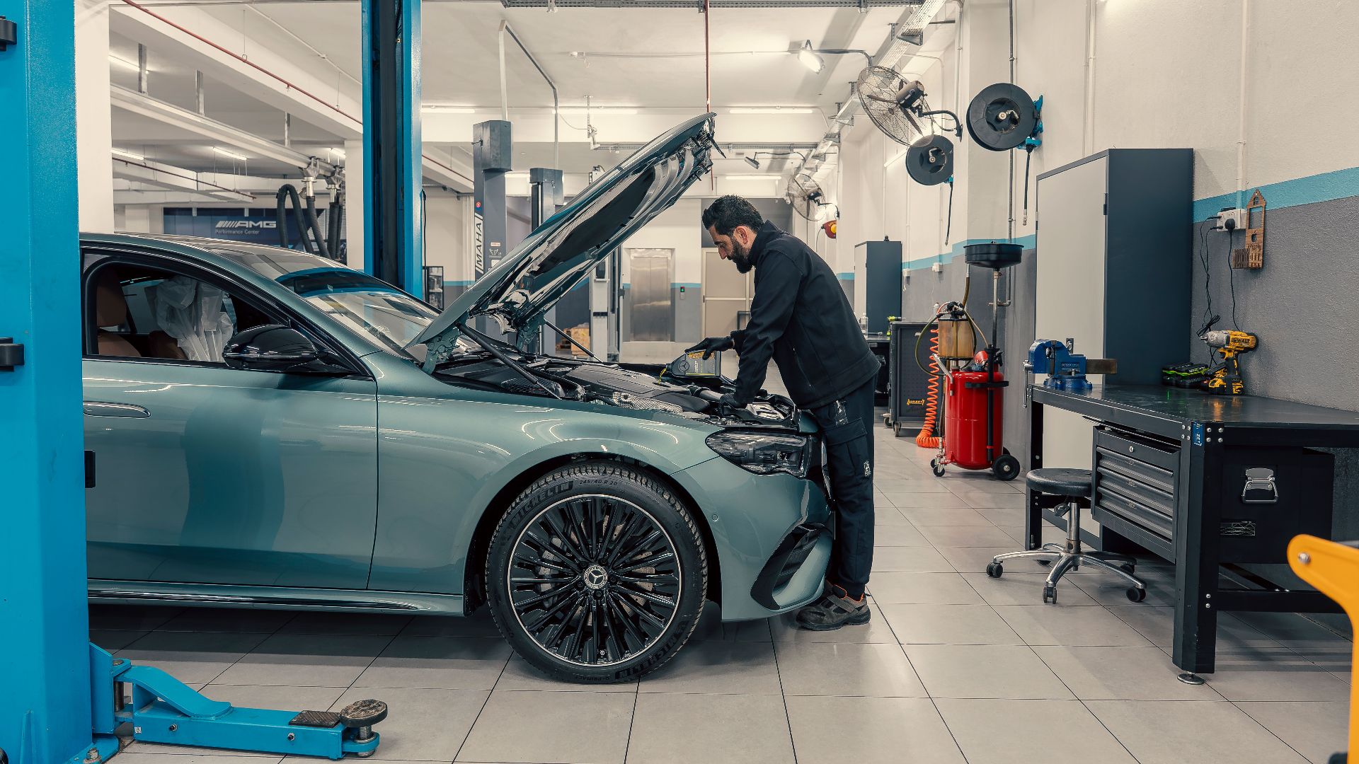 Mechanic inspecting a luxury car inside a well-equipped garage. Vehicle maintenance setting.