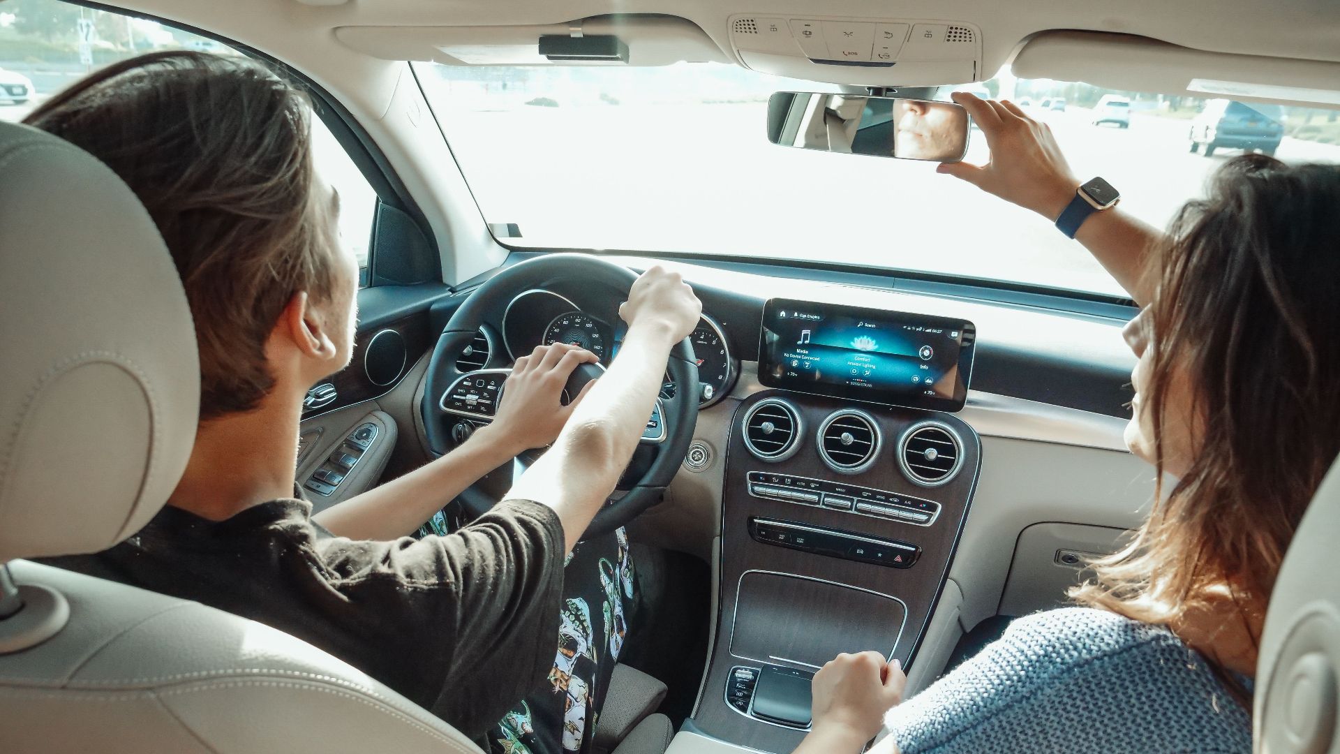 A young couple driving in a modern car, enjoying quality time together from a back view perspective.