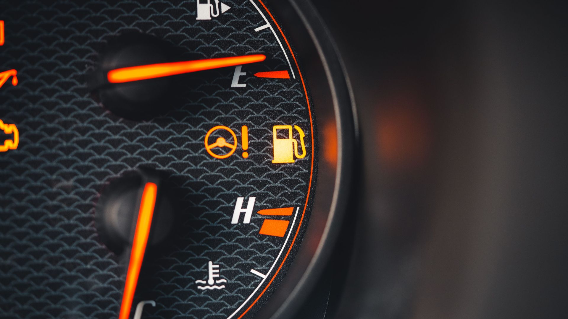 Detailed view of a car dashboard showing fuel and temperature indicators with glowing pictographs.
