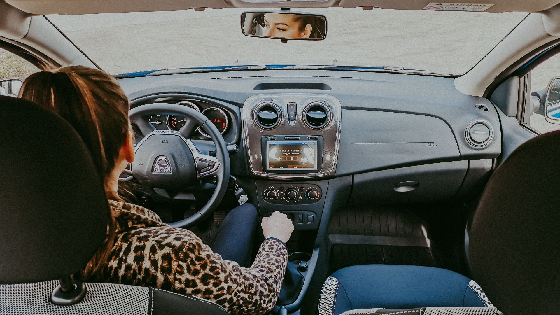 Back view of modern woman in stylish fur coat driving car confidently looking away