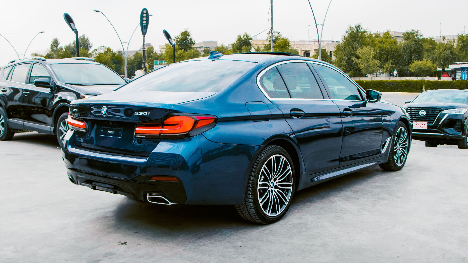 A sleek BMW sedan parked in an urban parking lot with other vehicles.
