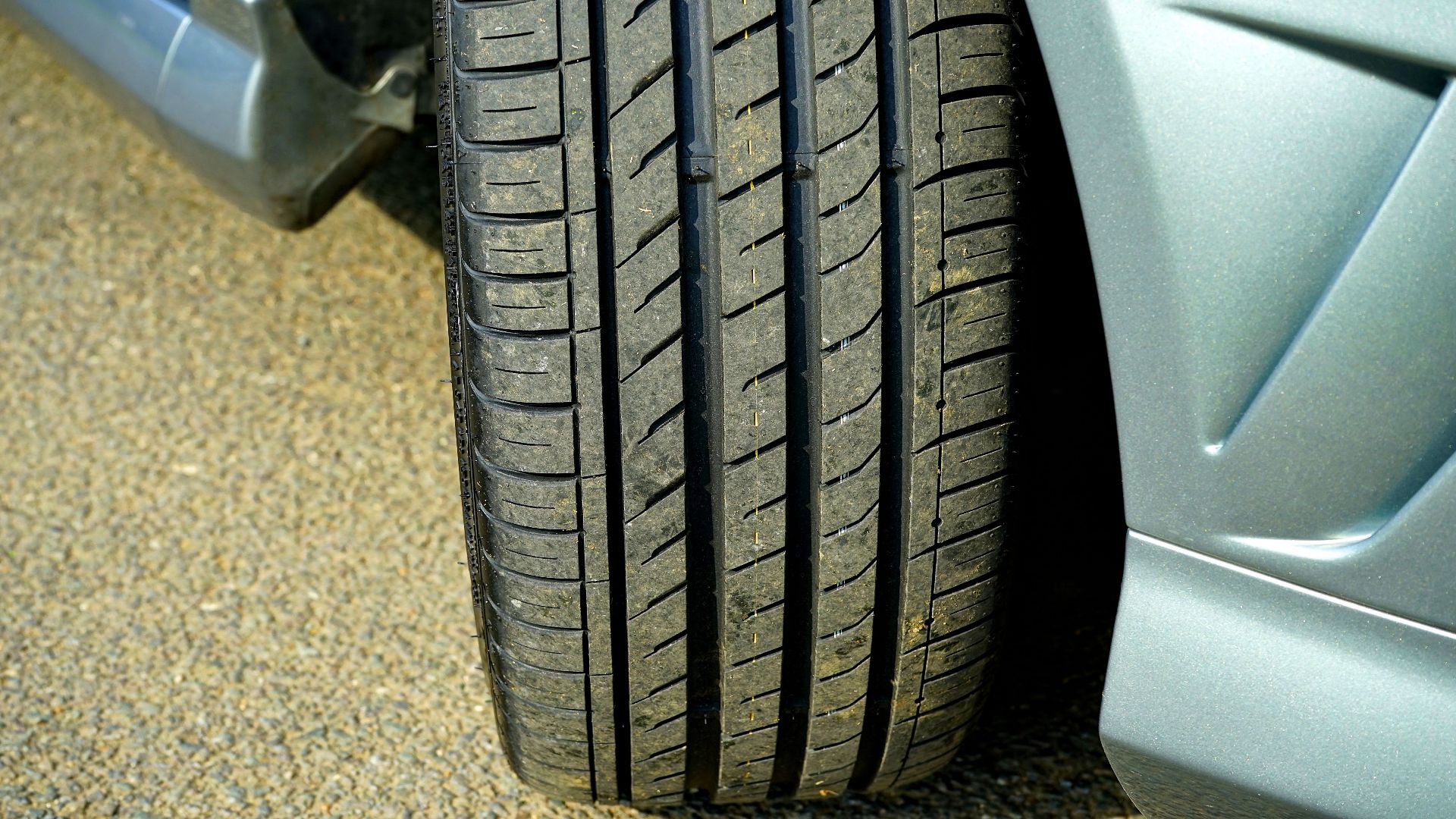 Detailed shot of a car tire on a clean asphalt surface, highlighting tire tread.