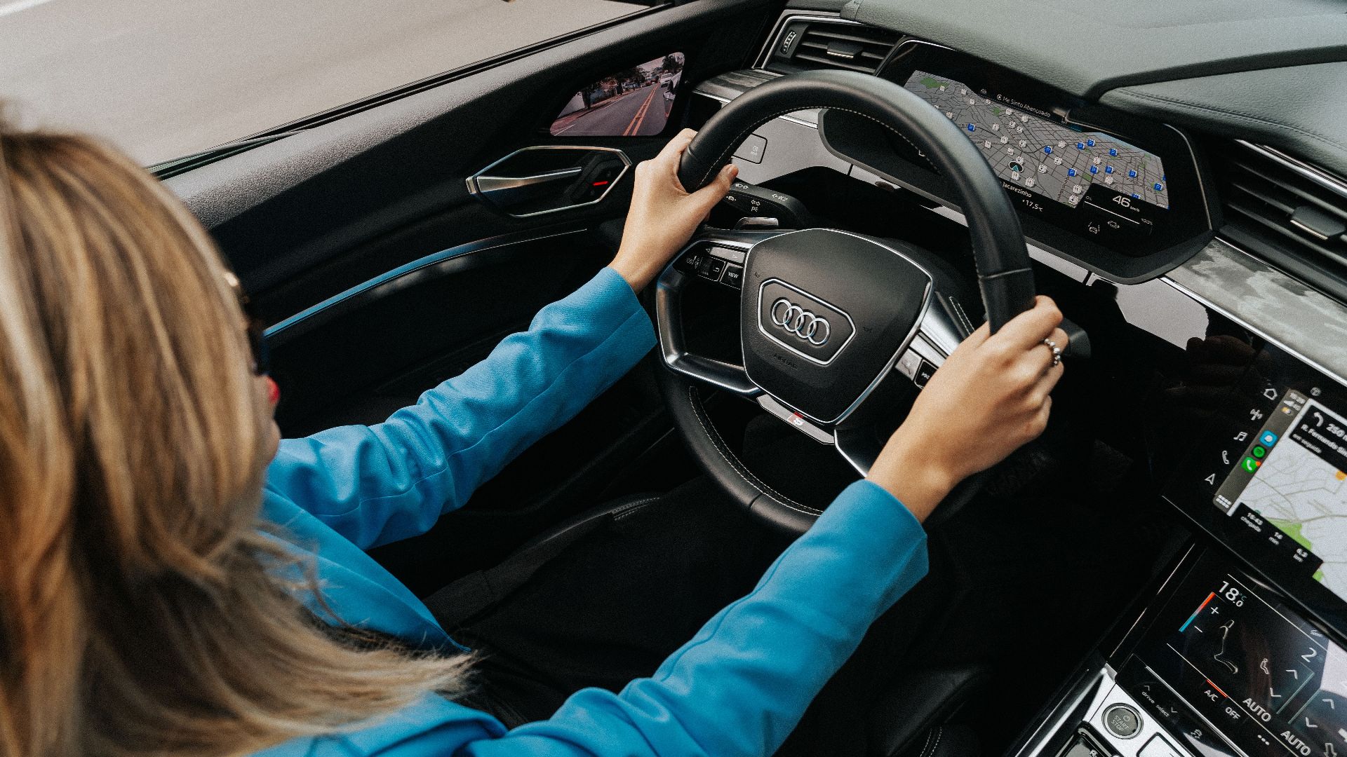 High angle view of a woman driving a modern Audi car, showcasing the dashboard and steering wheel.