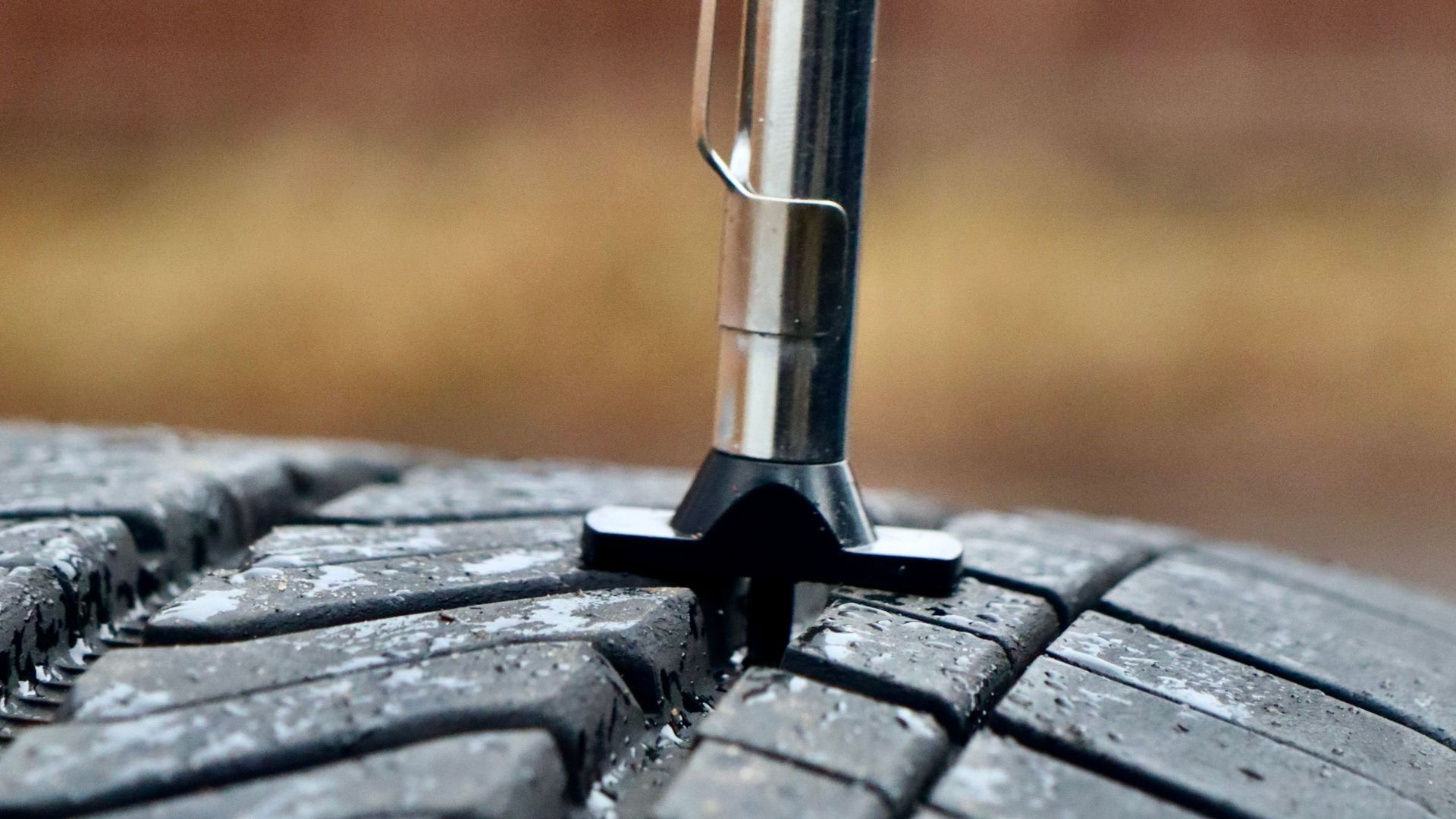 Close-up of a tire tread depth gauge in a tire illustrating measurement accuracy.