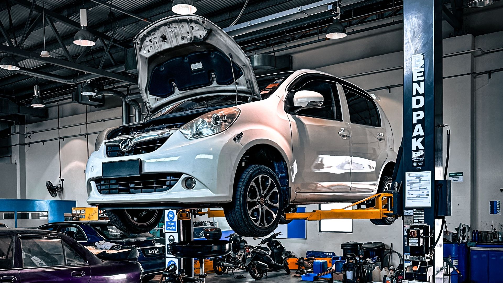 A car is lifted on a hydraulic lift in a well-equipped auto repair shop.