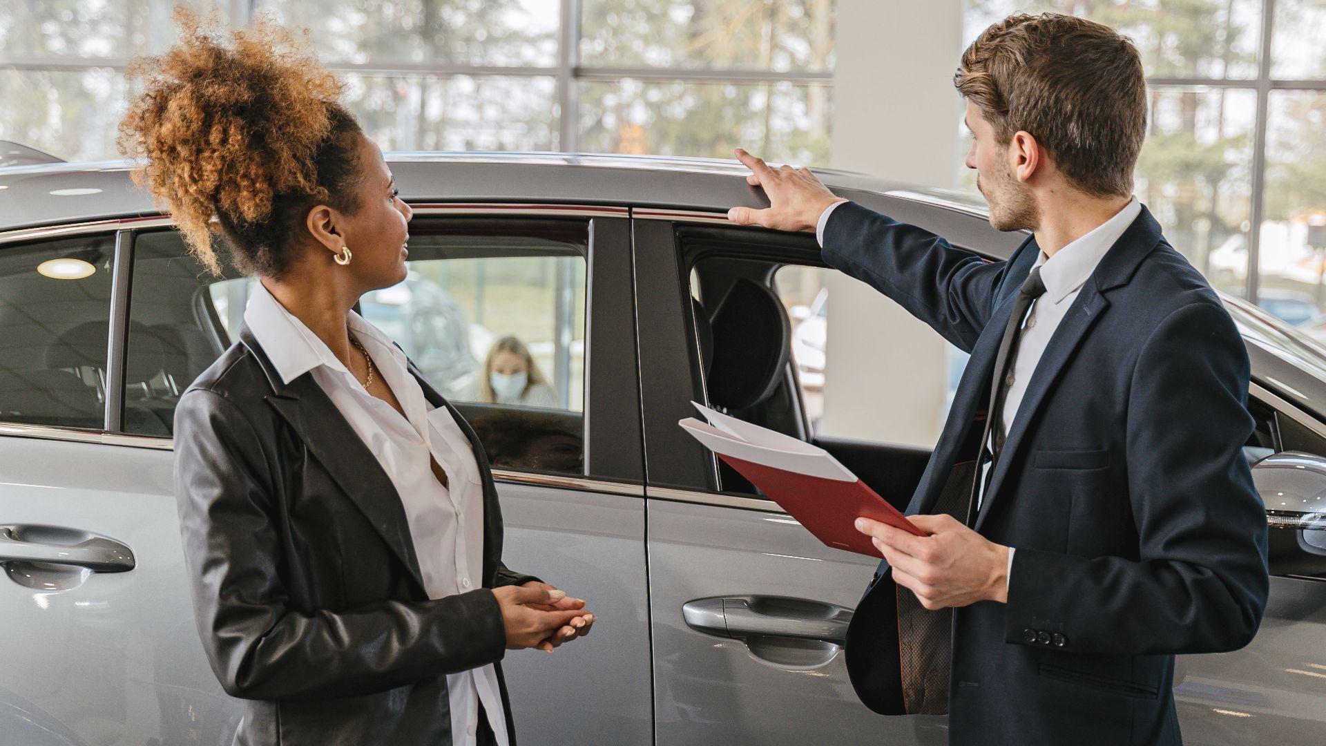 A woman and a car salesman discuss vehicle options inside a dealership.