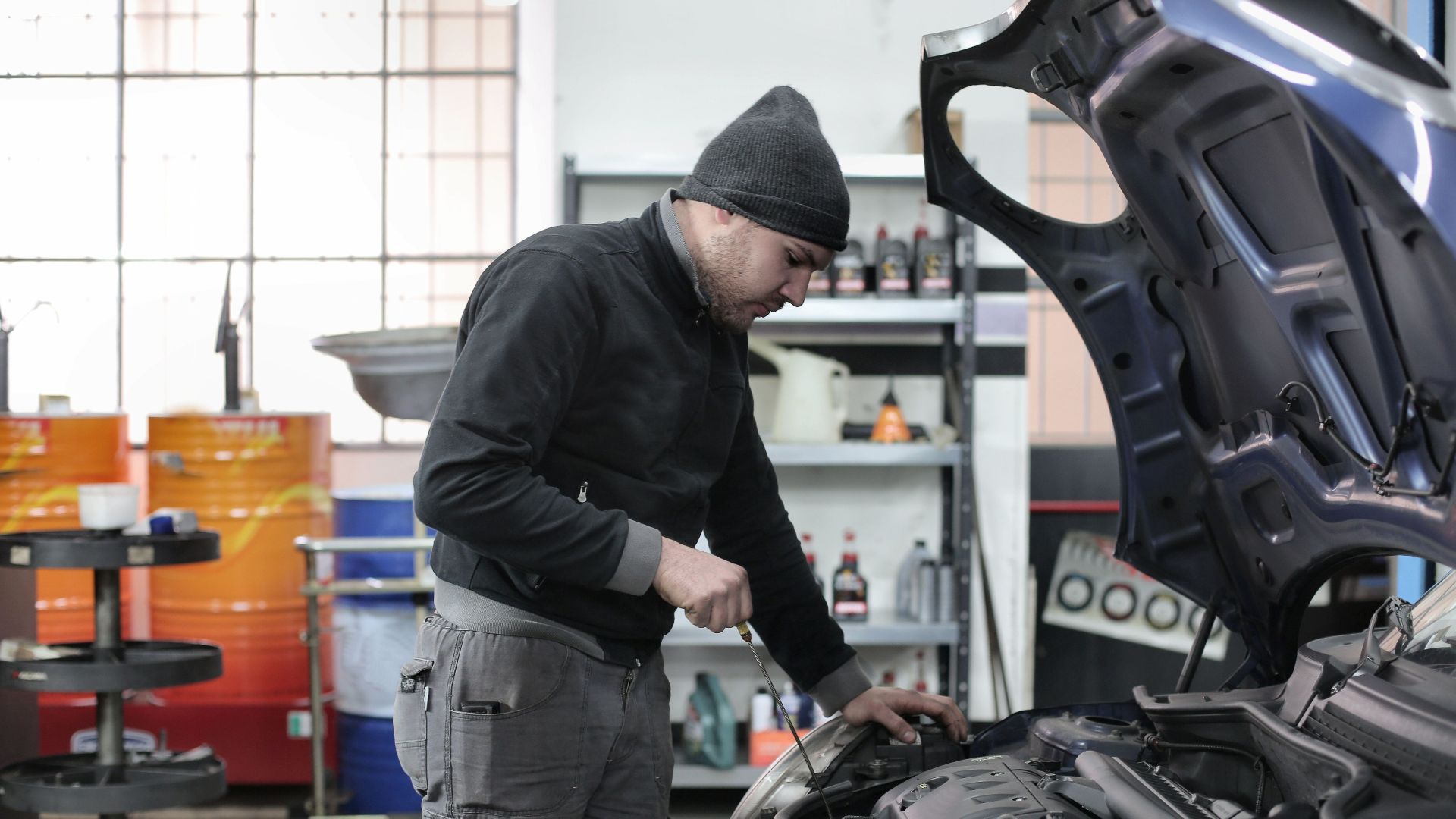 Mechanic checking a car engine in a garage, ensuring quality maintenance and repair.