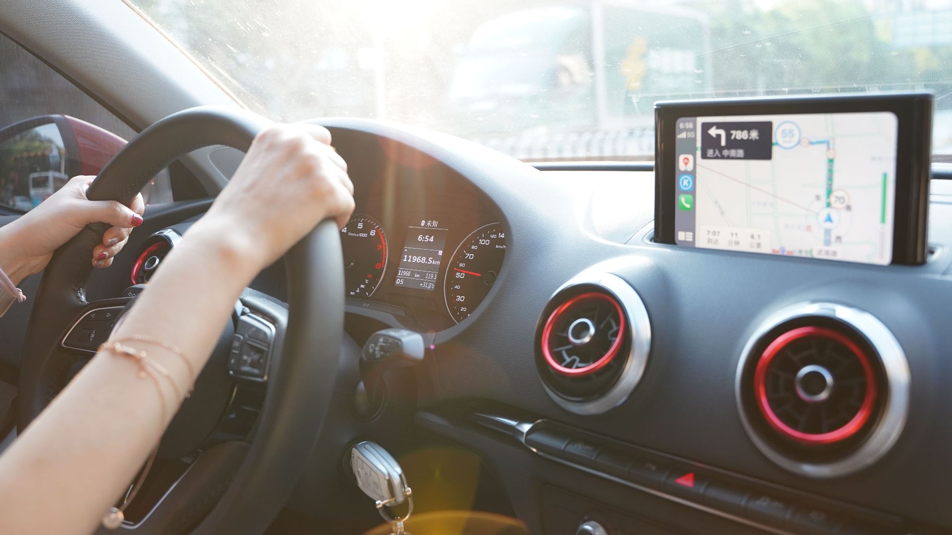 Hands on steering wheel using GPS navigation inside car during road trip.