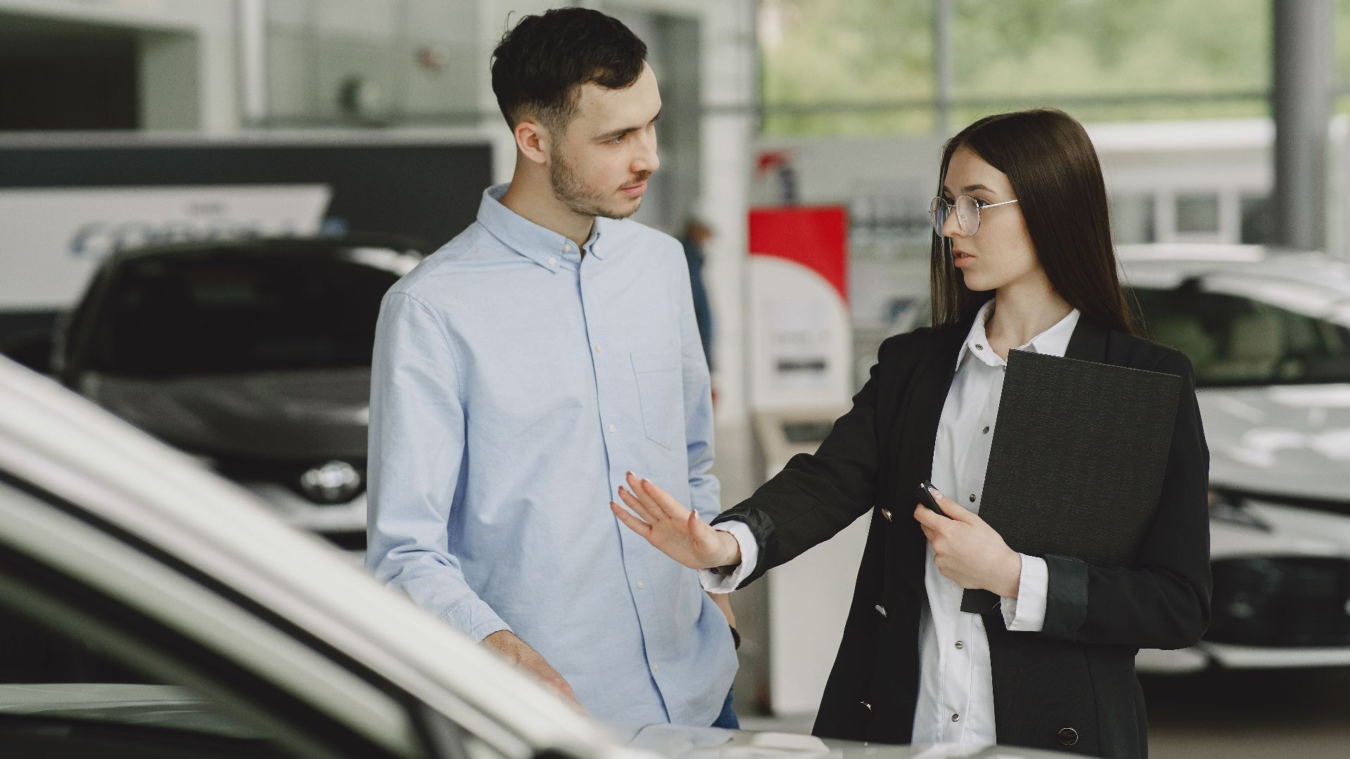 A salesperson and customer discussing car features in a dealership setting.