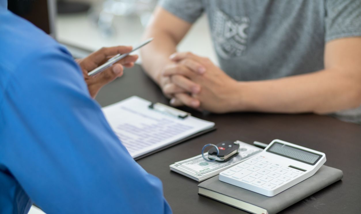 The car dealers of the car showrooms bring the car sales contract documents to the customers and explain the loan and interest rates to the customers before signing the sales contract for accuracy.