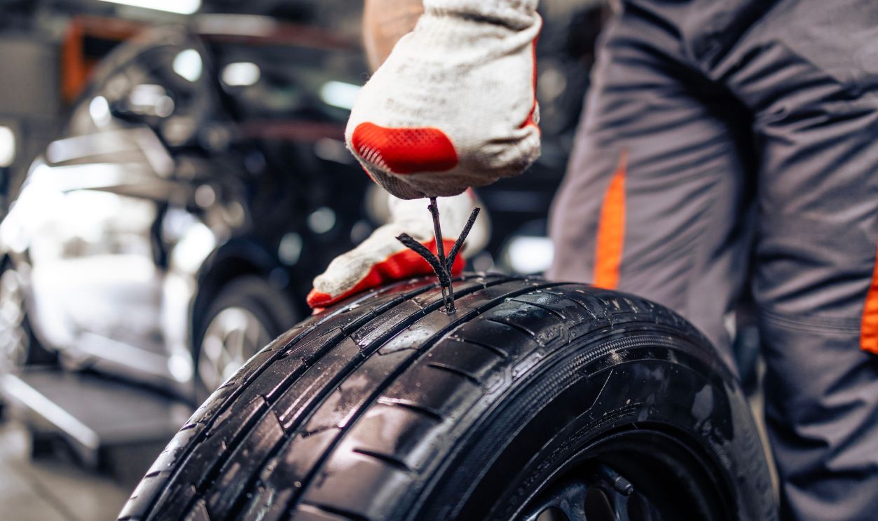 Replacing damaged car tire. Close up view of repairman using tire repair kit to fix damaged tire.