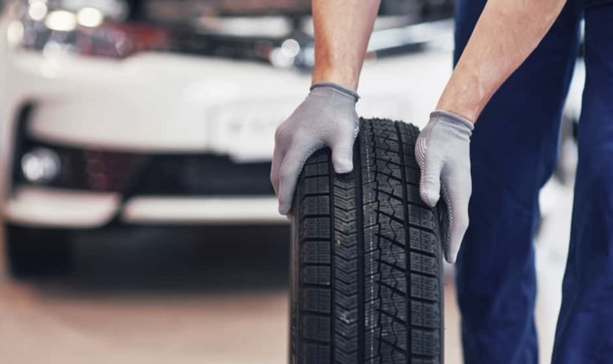 Shutterstock-1009020145, Mechanic holding a tire tire at the repair garage. replacement of winter and summer tires.