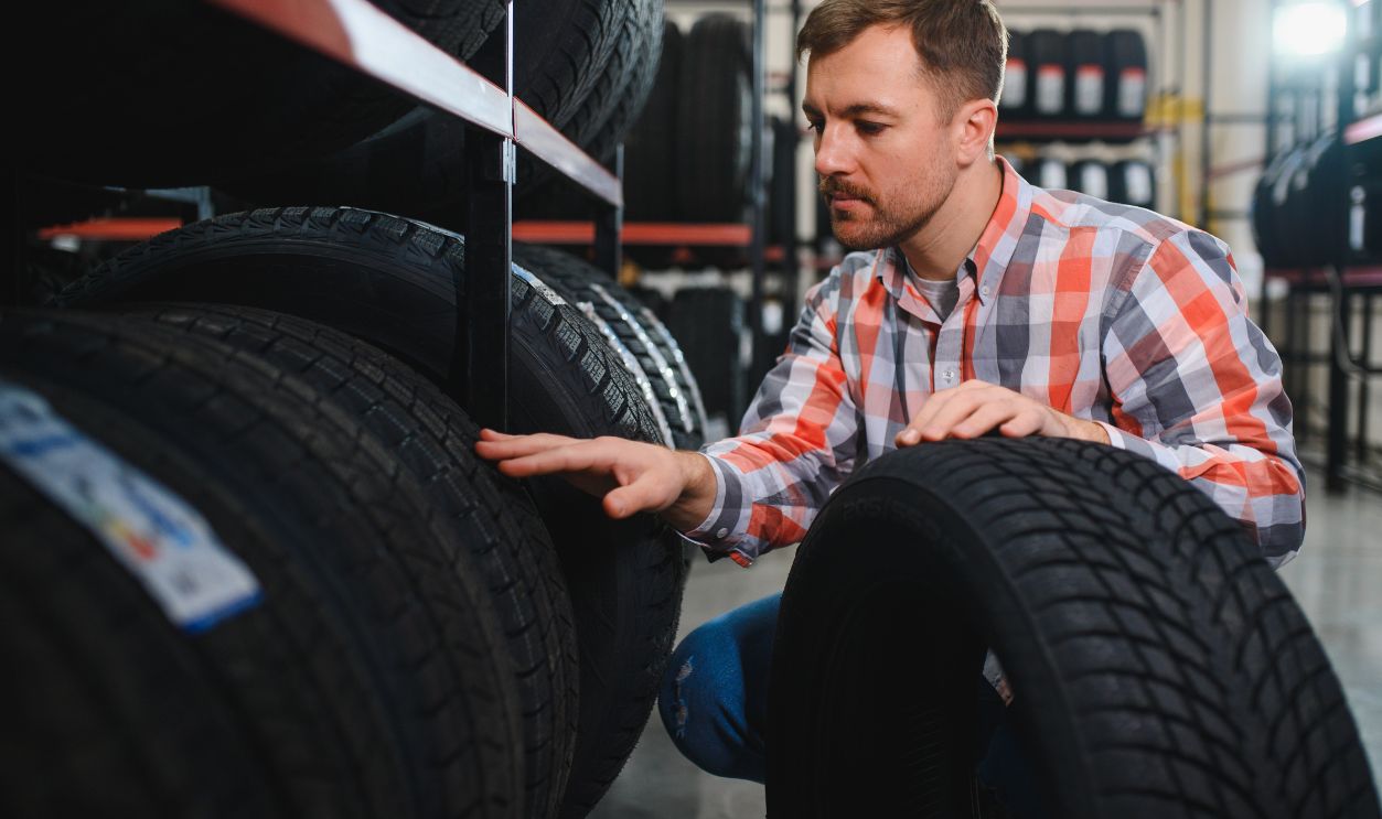 Shutterstock-2608438377, Portrait young man customer examining brand and product characteristics while buying new tires in auto department of dealership. Male client choosing car accessories shopping mall.