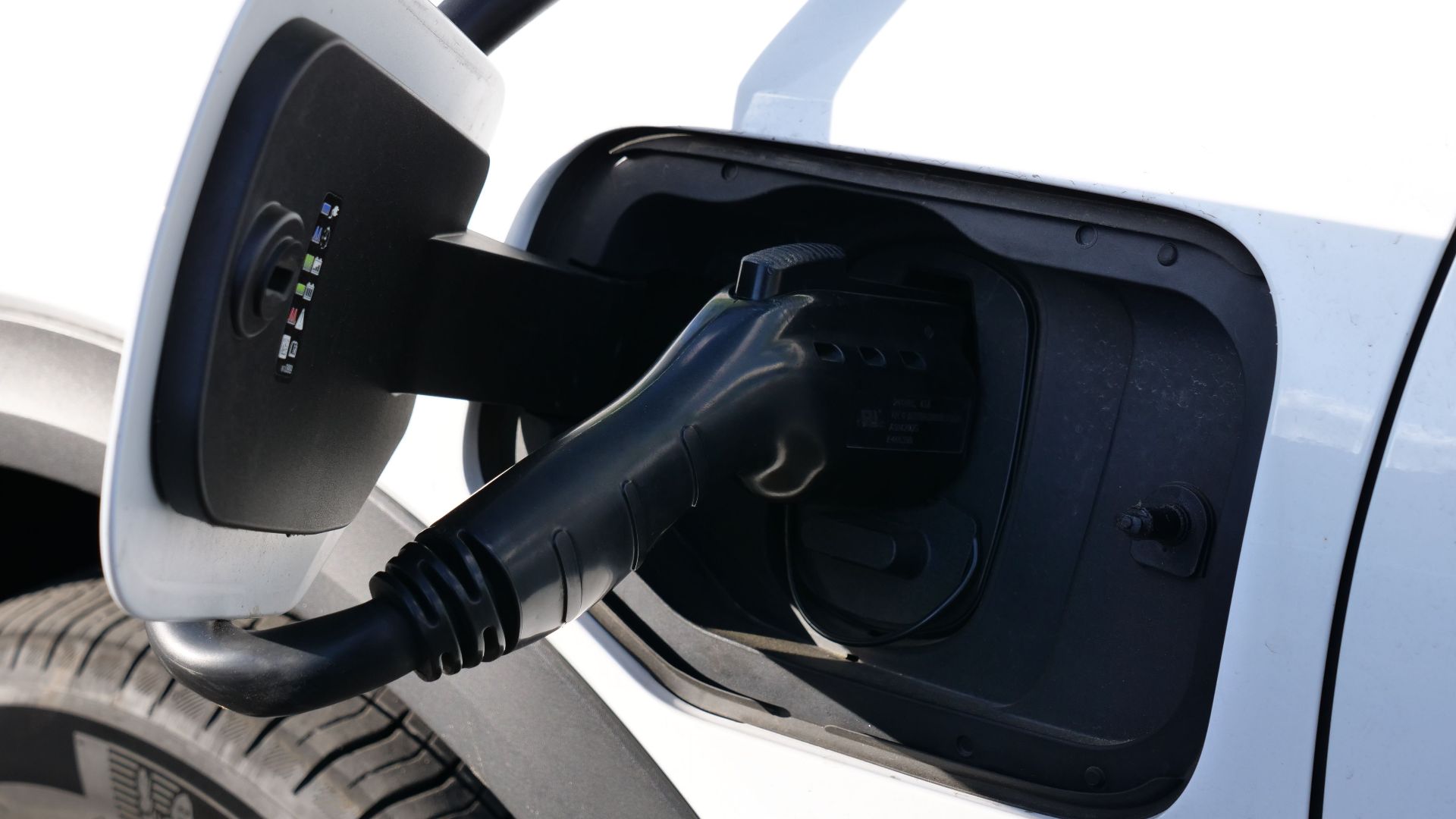 Close-up view of an electric vehicle charging with a focus on the connector and charging port.